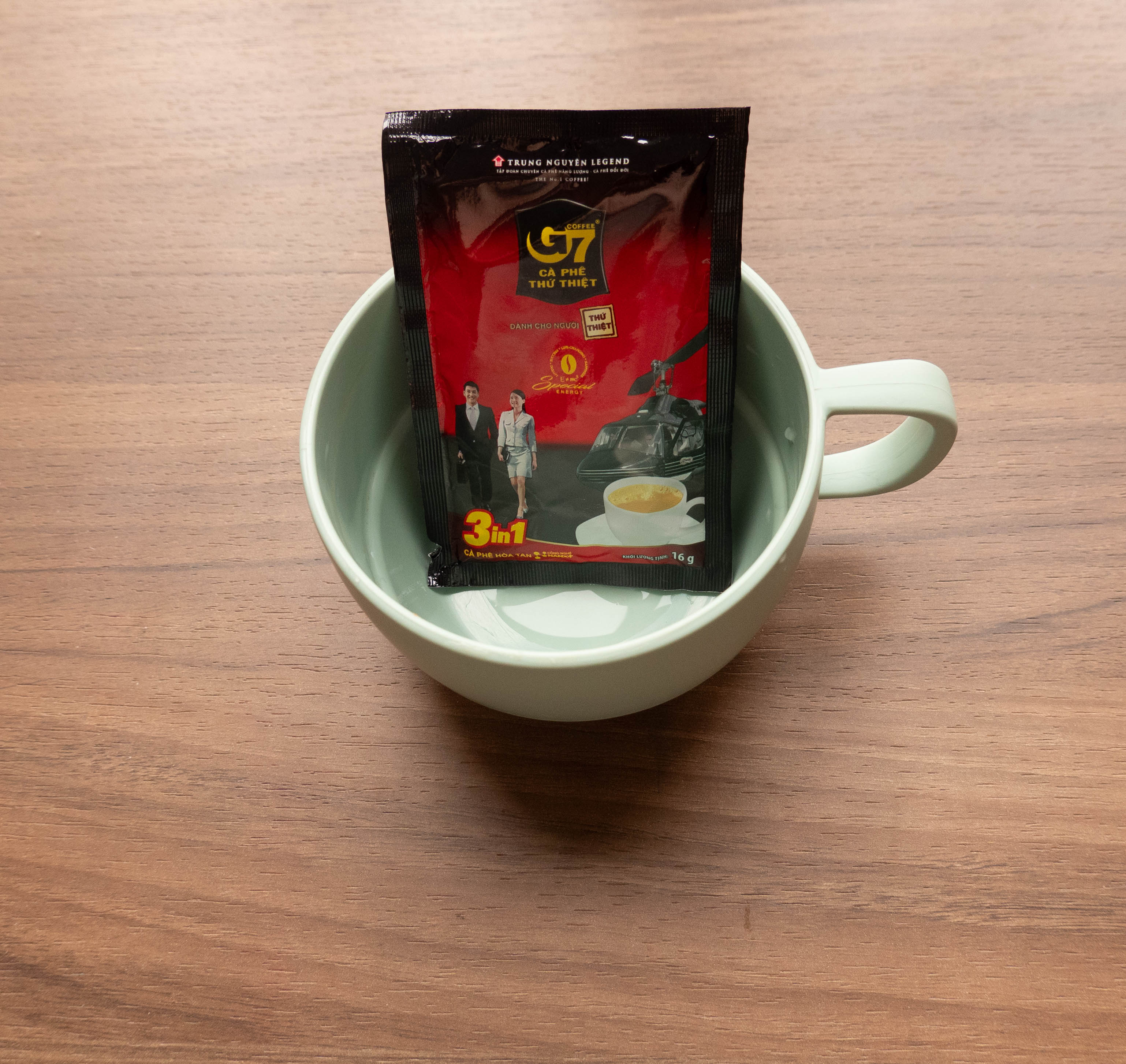 Light green coffee cup with unopened package of G7 instant coffee inside cup 