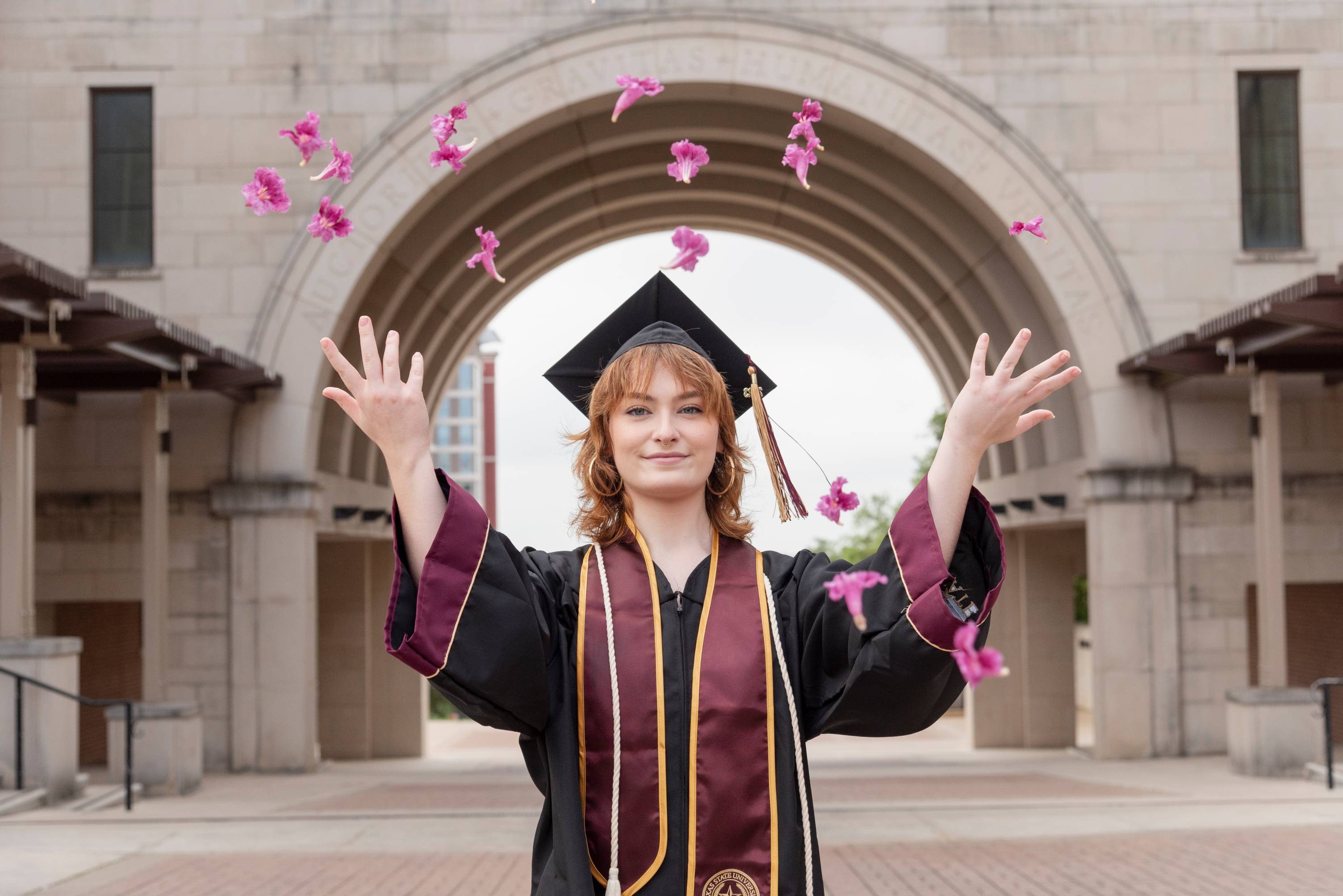 student graduate tossing flowers in air