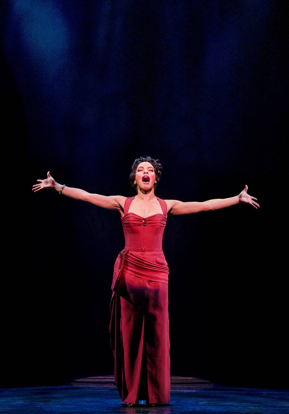 woman in red dress singing with her arms stretched out