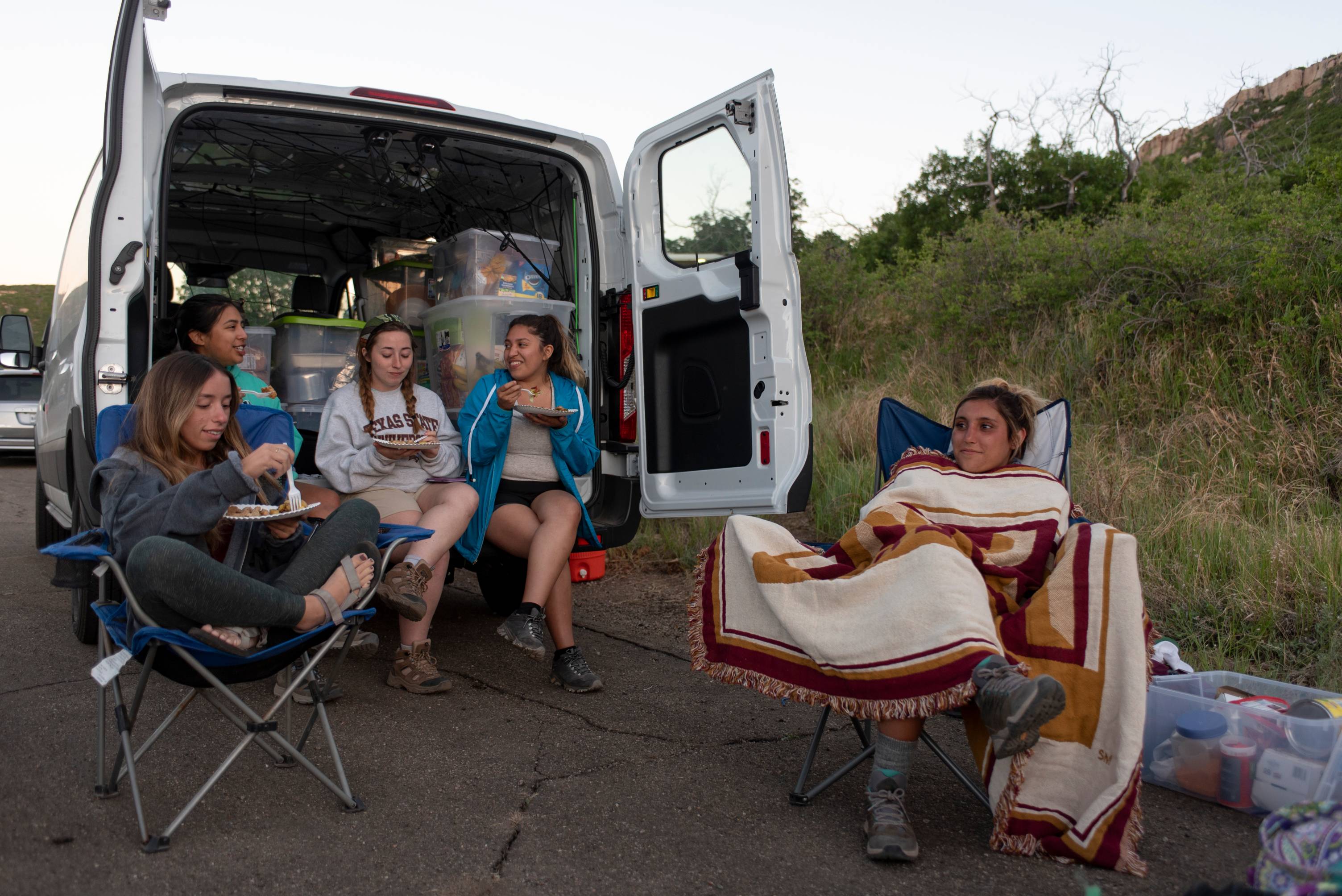 5 students sit outside a 15-passenger van used to travel to Mesa Verde National Park 