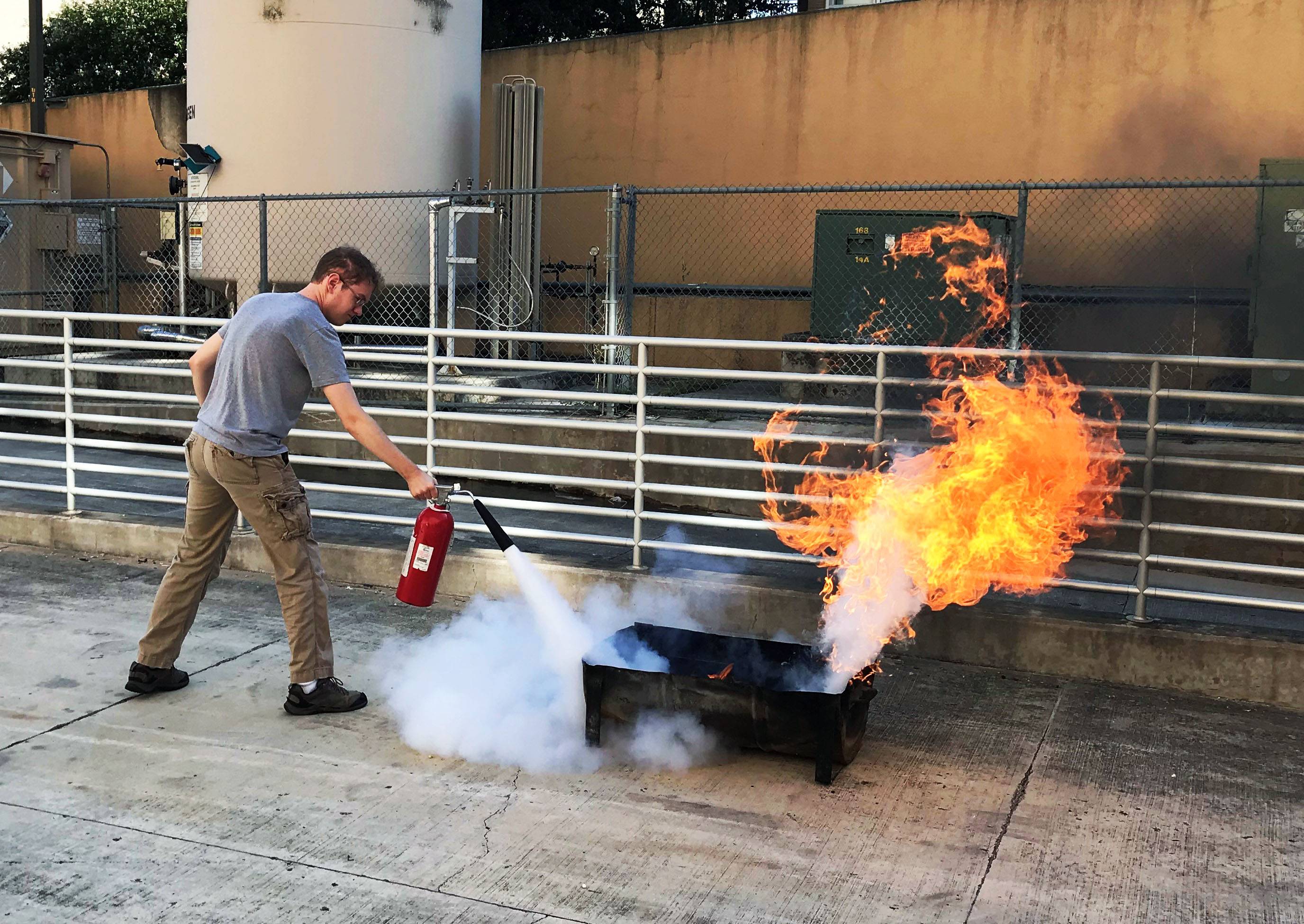 Student uses a fire extinguisher to put out a fire during a fire extinguisher training 