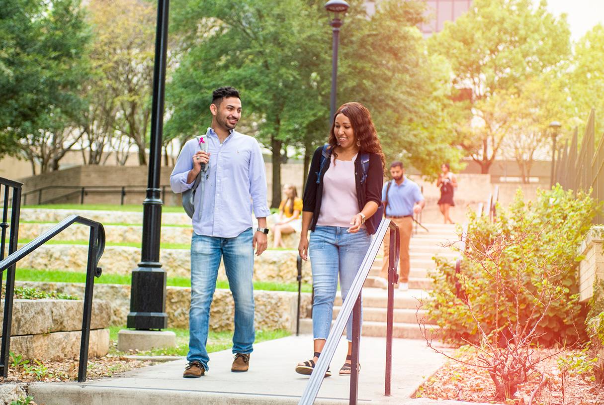 man and female student walking down stairs on txst campus