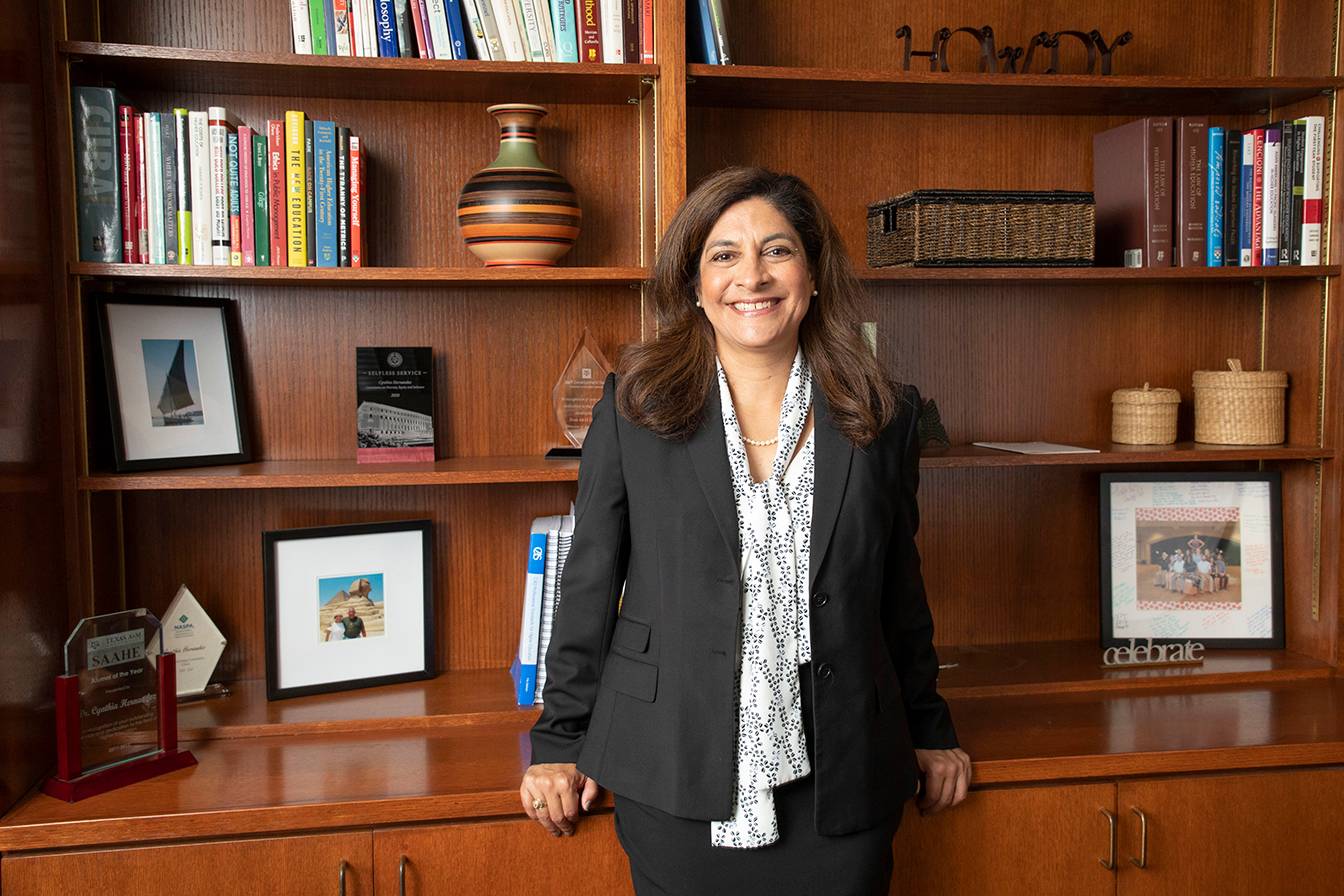 woman in business attire standing next to large wooden bookcase