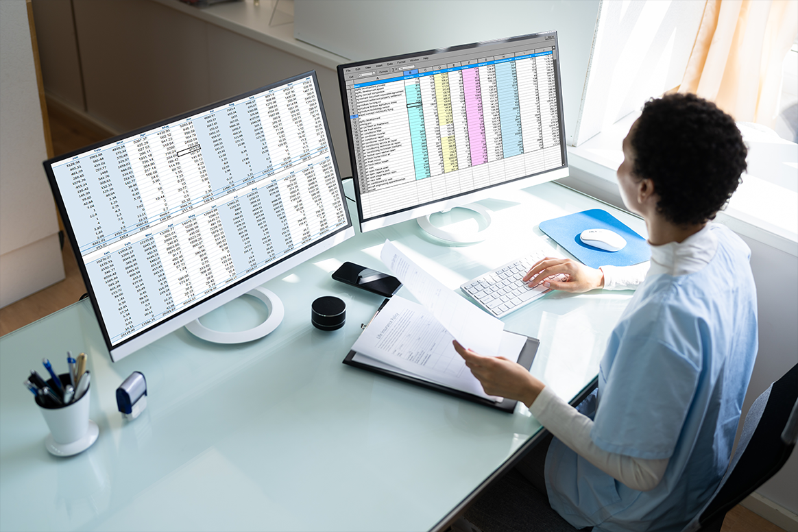 A person siting in front of a computer with medical data on it. 