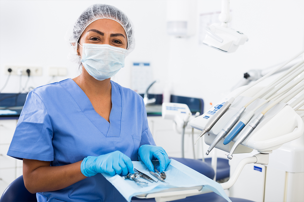 A dental assistant holding dental tools.