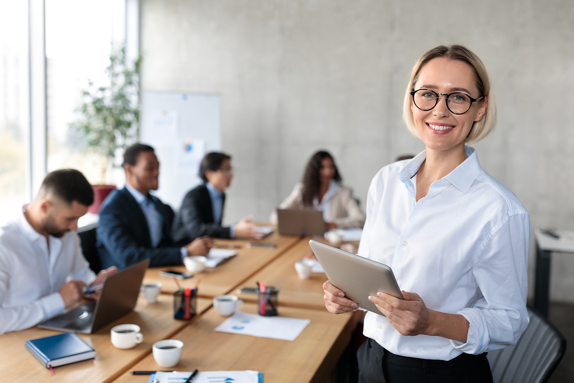 A woman standing in front of a room of people in work attire. 