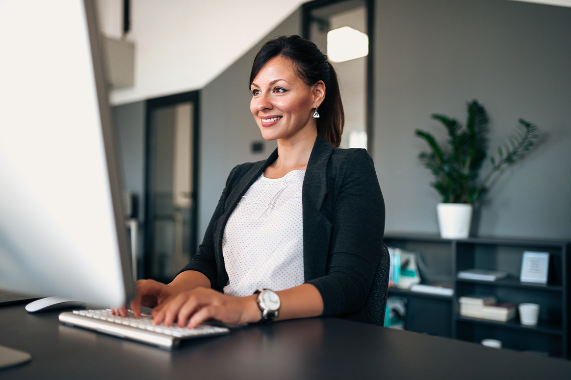 A woman in suit sitting at a desk.