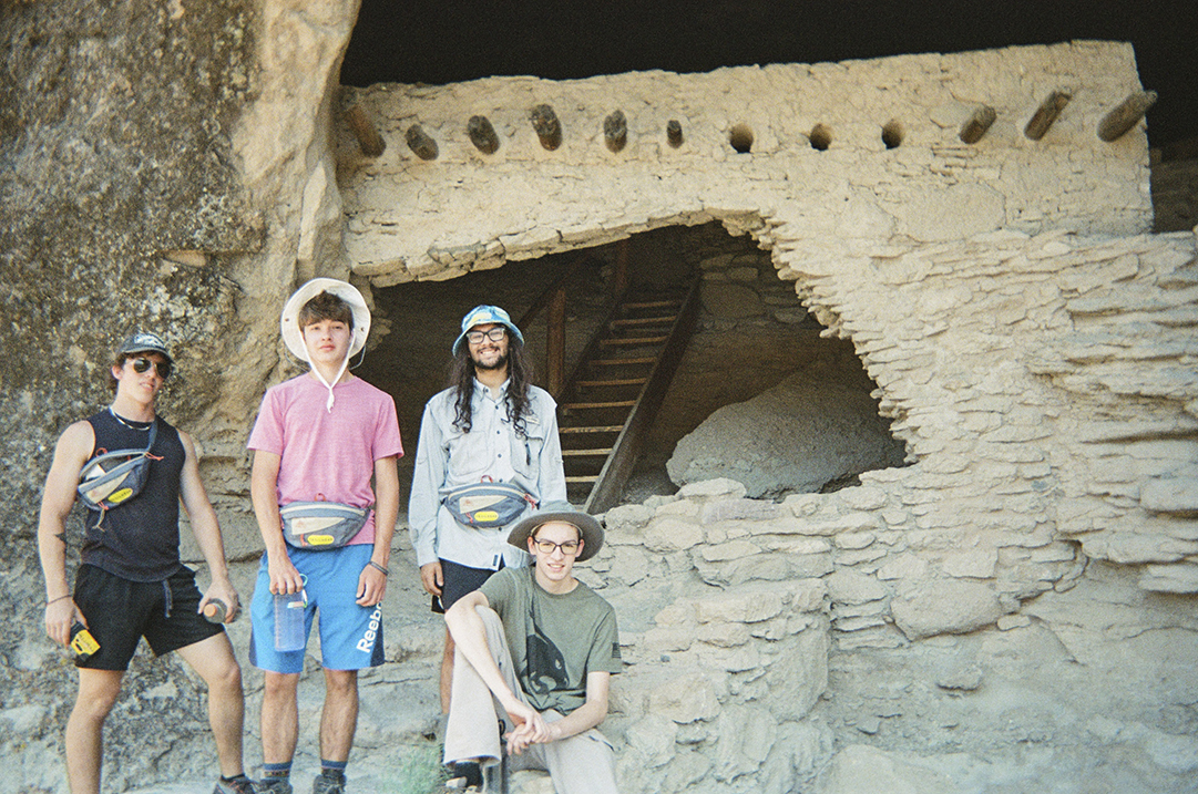four people standing next to new mexico adobe housing