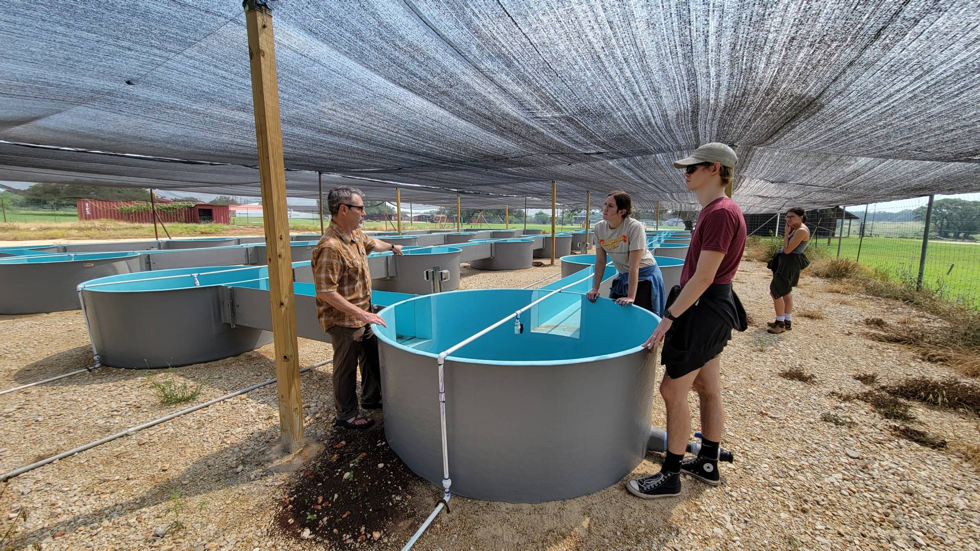 Photo of Dr. Nowlin talking to his colleagues at the outdoor river systems lab at Freeman Ranch