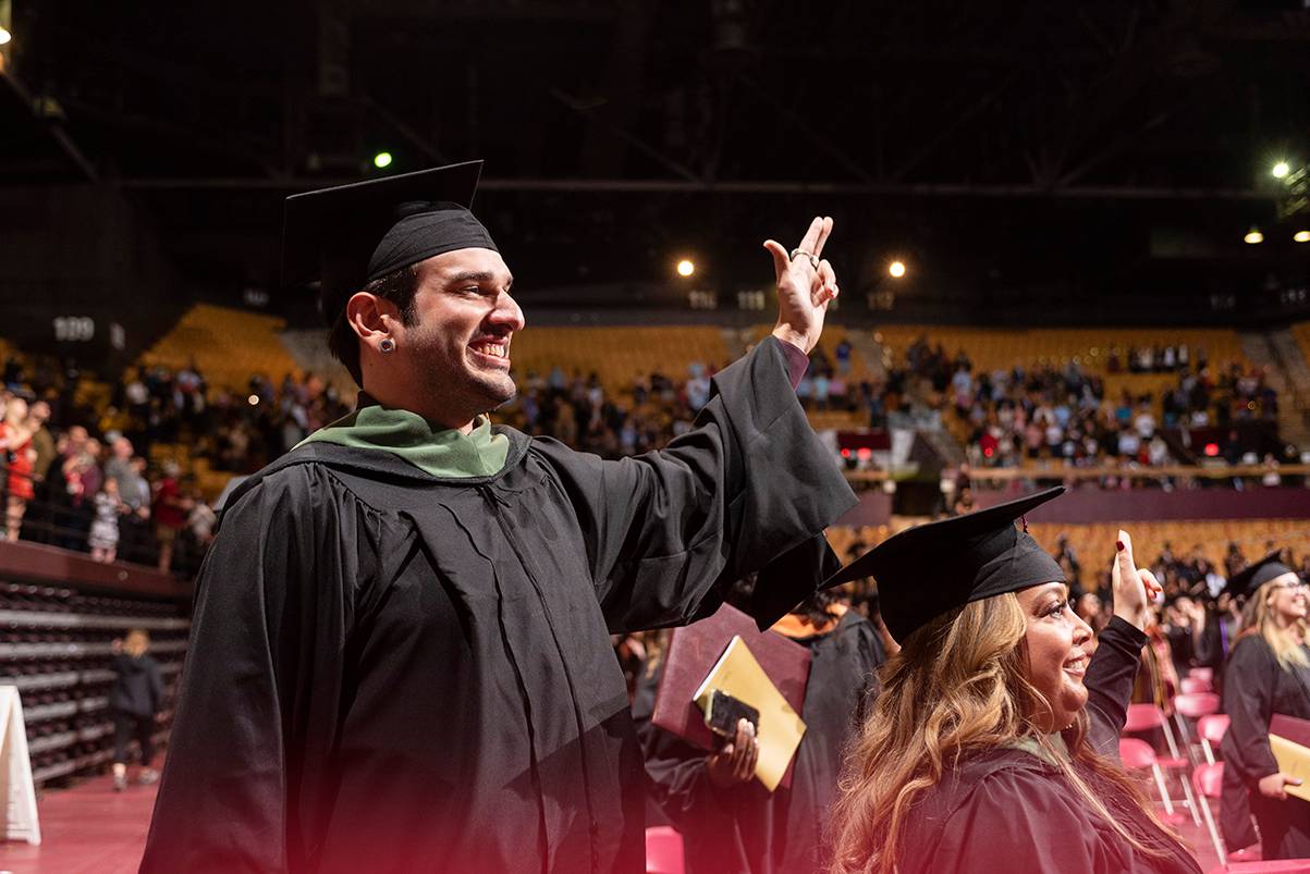 graduates smiling with txst hand sign up