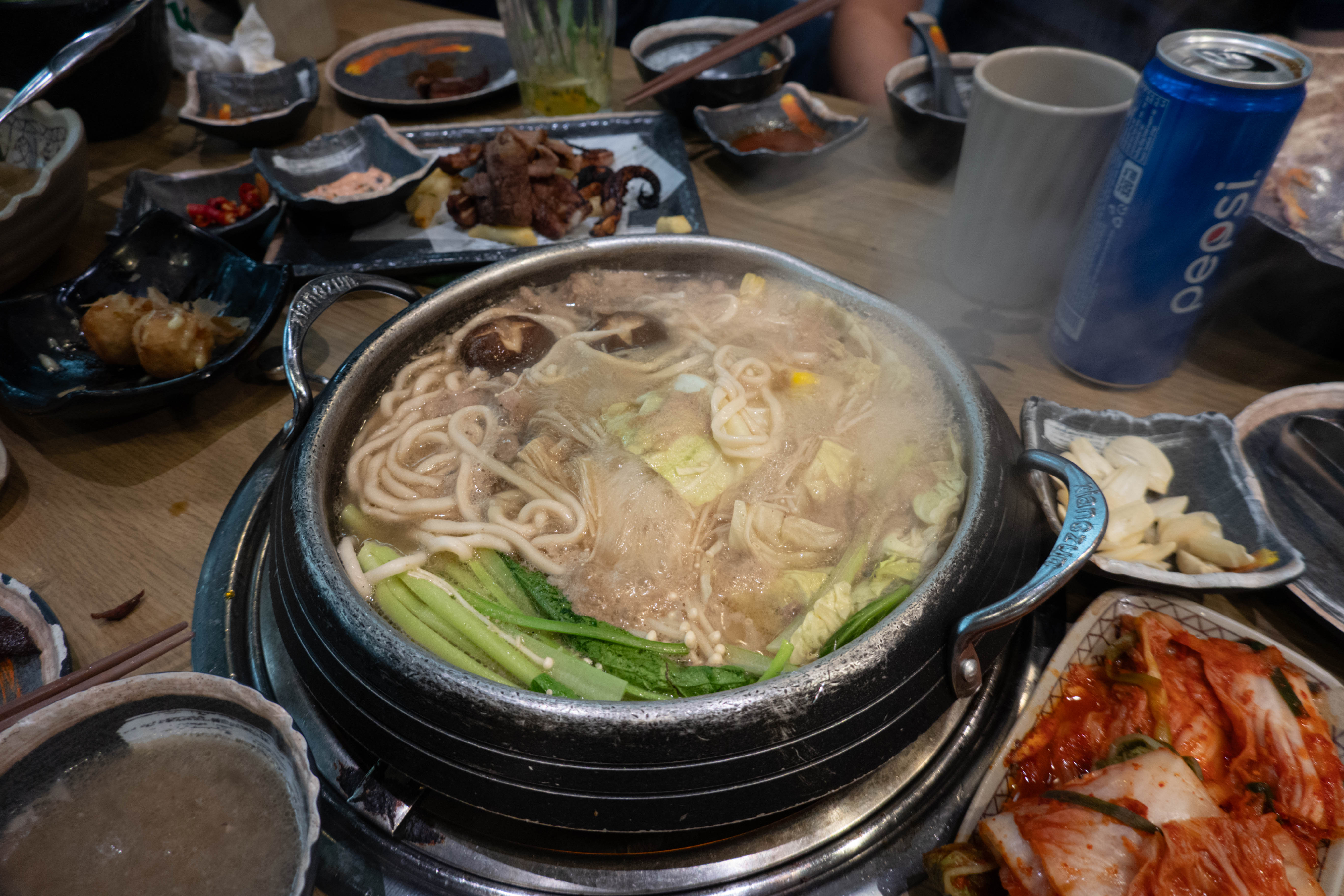 Picture of boiling hotpot with noodles, mushrooms, and greens
