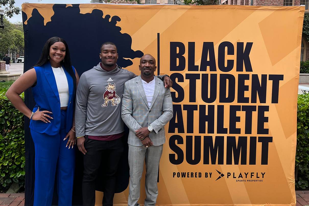 three people posing for photo next to sign reading "black student athlete summit"
