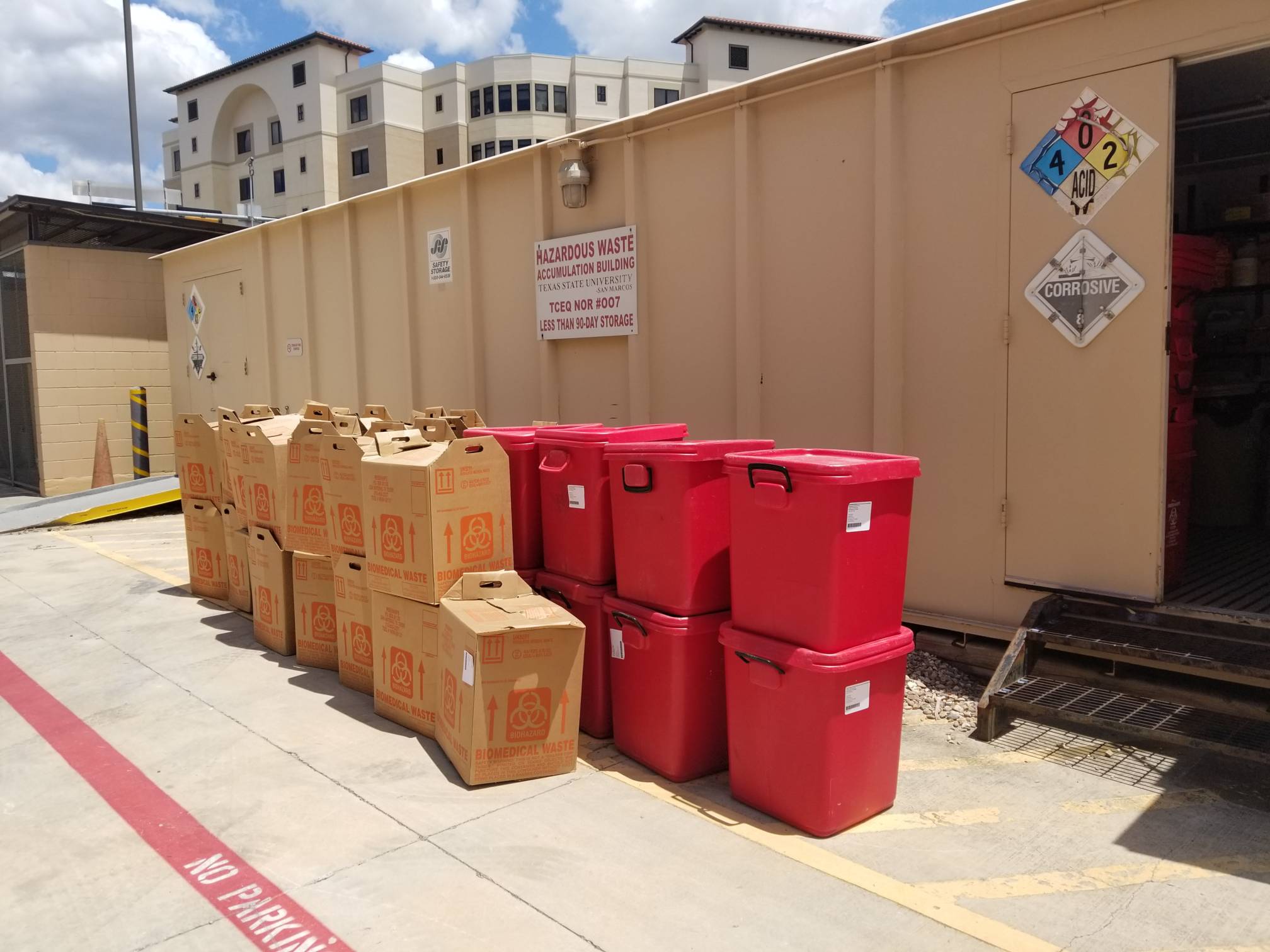 Brown biowaste boxes and red biowaste bins stacked up awaiting pick up