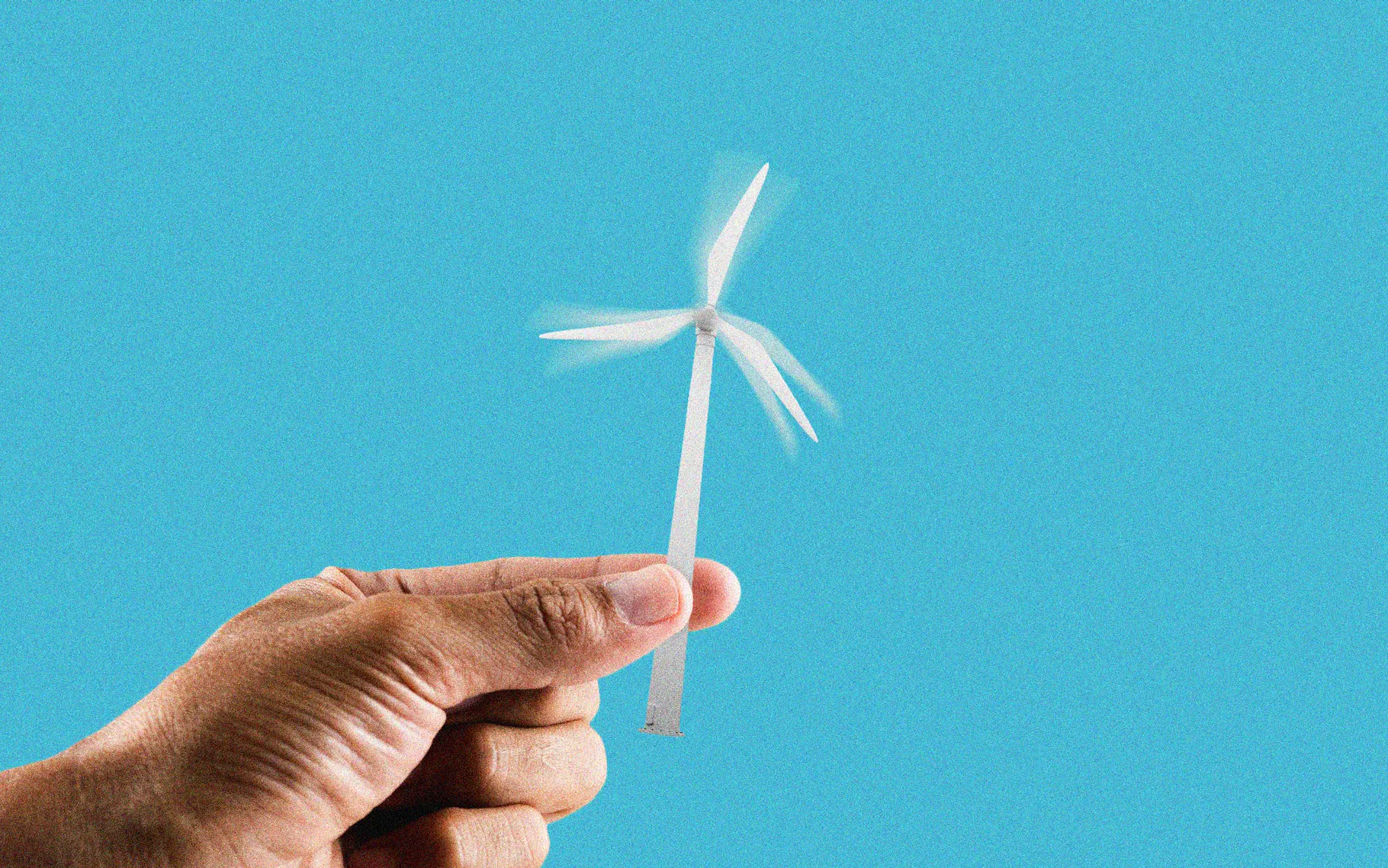 Person holding small wind turbine with a blue background