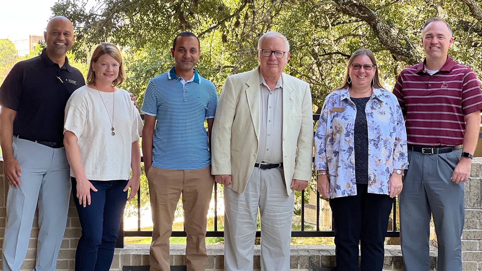 Six faculty members posing outdoors.
