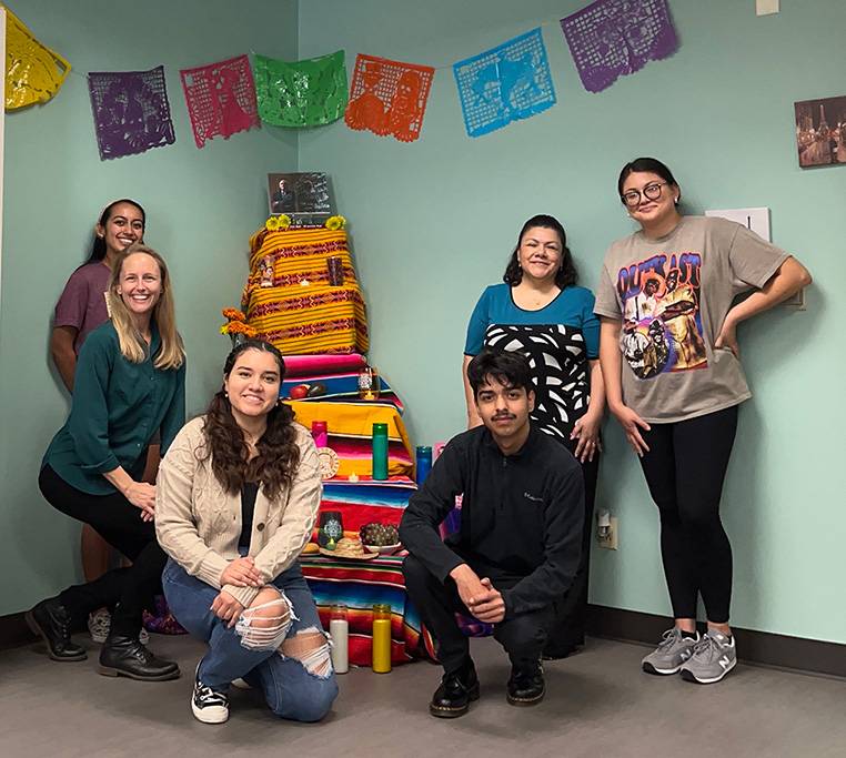 Several Sigma Delta Pi members posing for a photo in a decorated room.