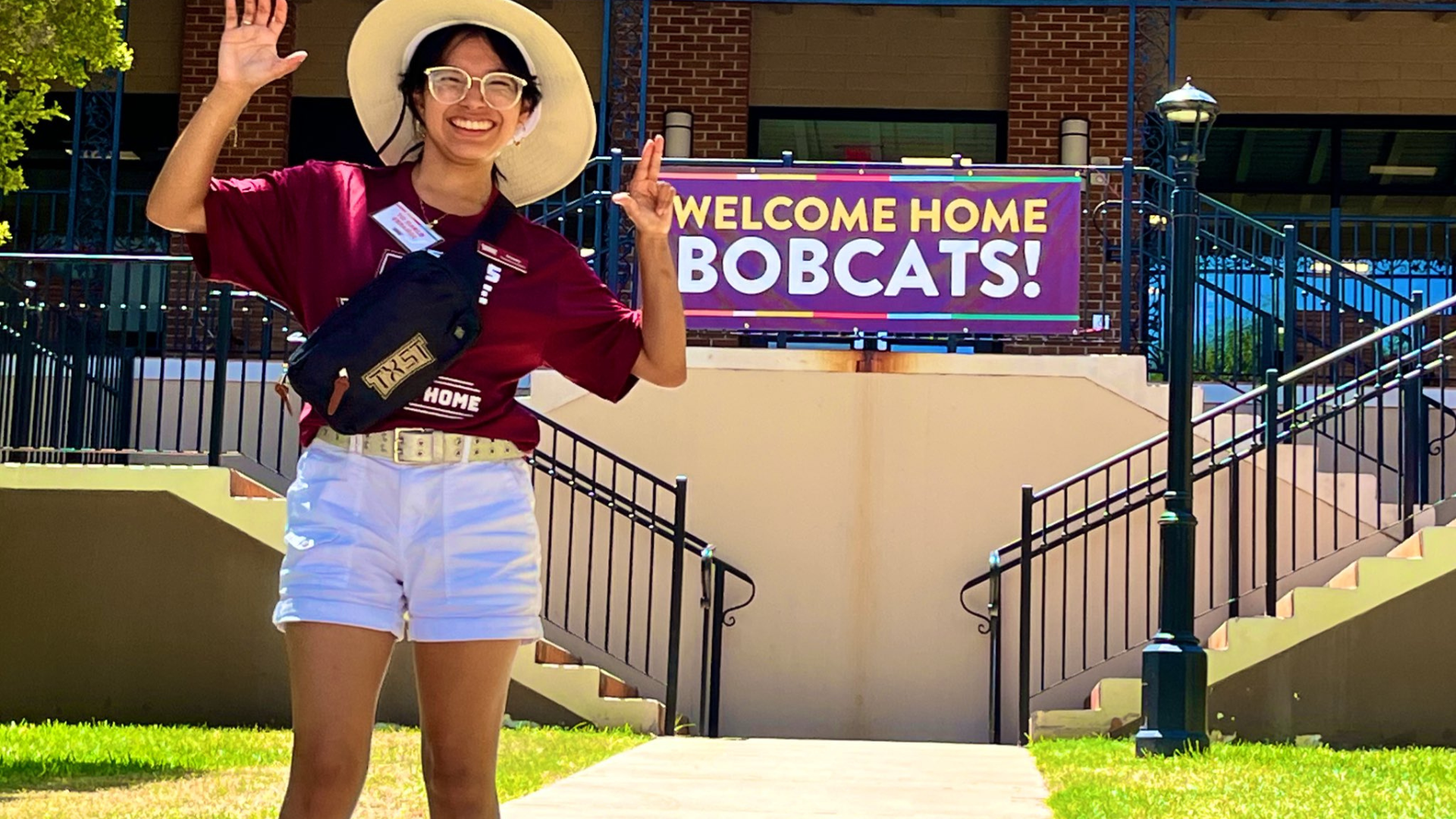 A TXST student ambassador shows the "Eat 'Em Up" and "Heart of Texas" handsigns during Move-In Day.