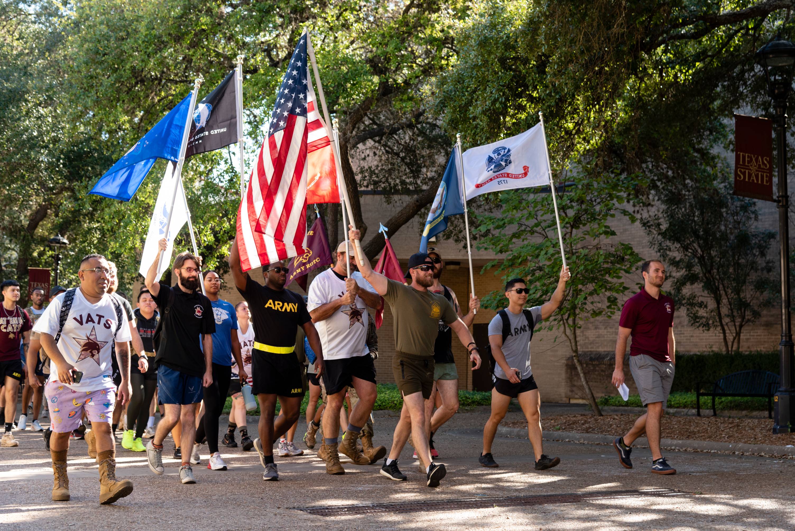 student veterans hiking across campus while holding flags