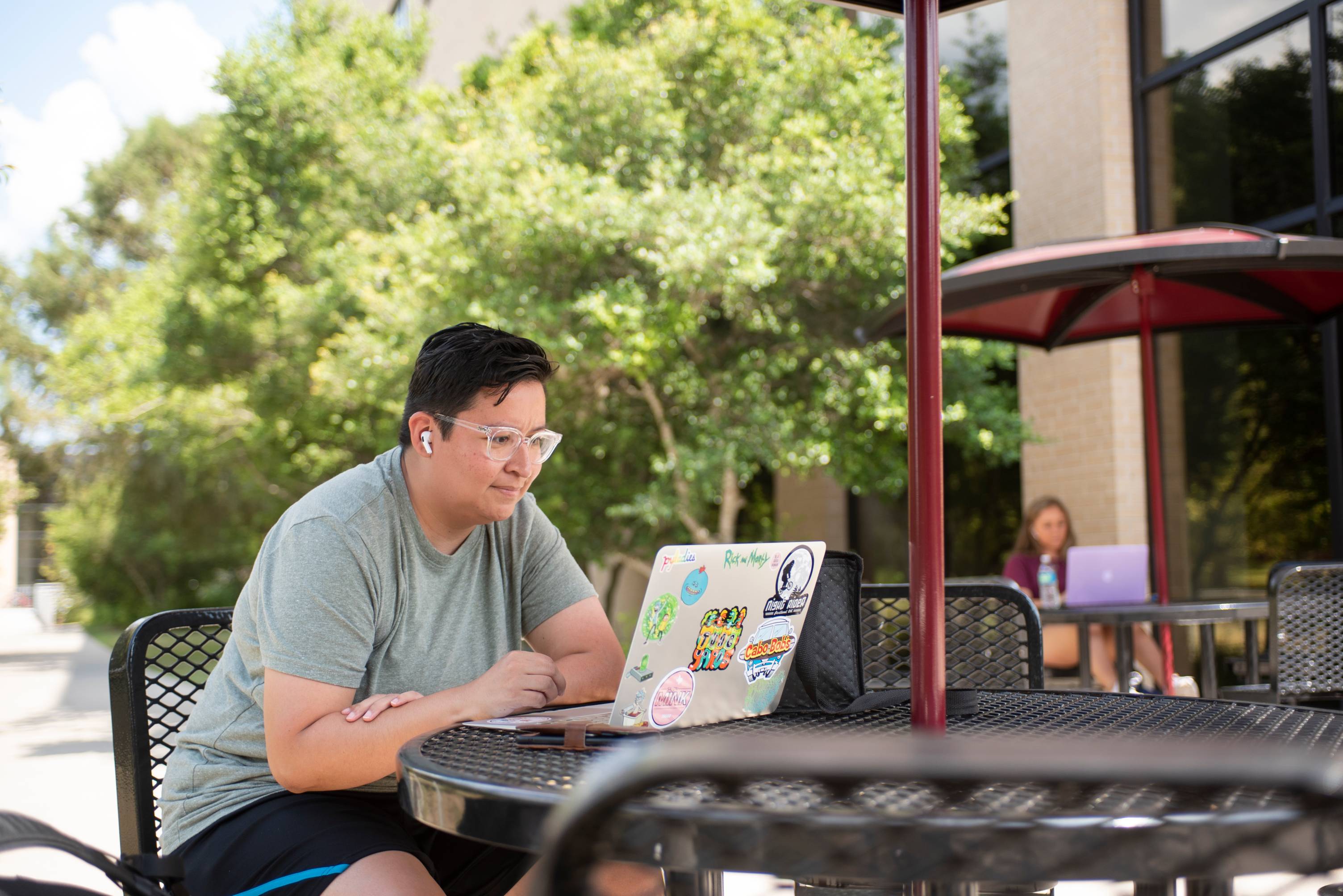Student working on their laptop at a table outside