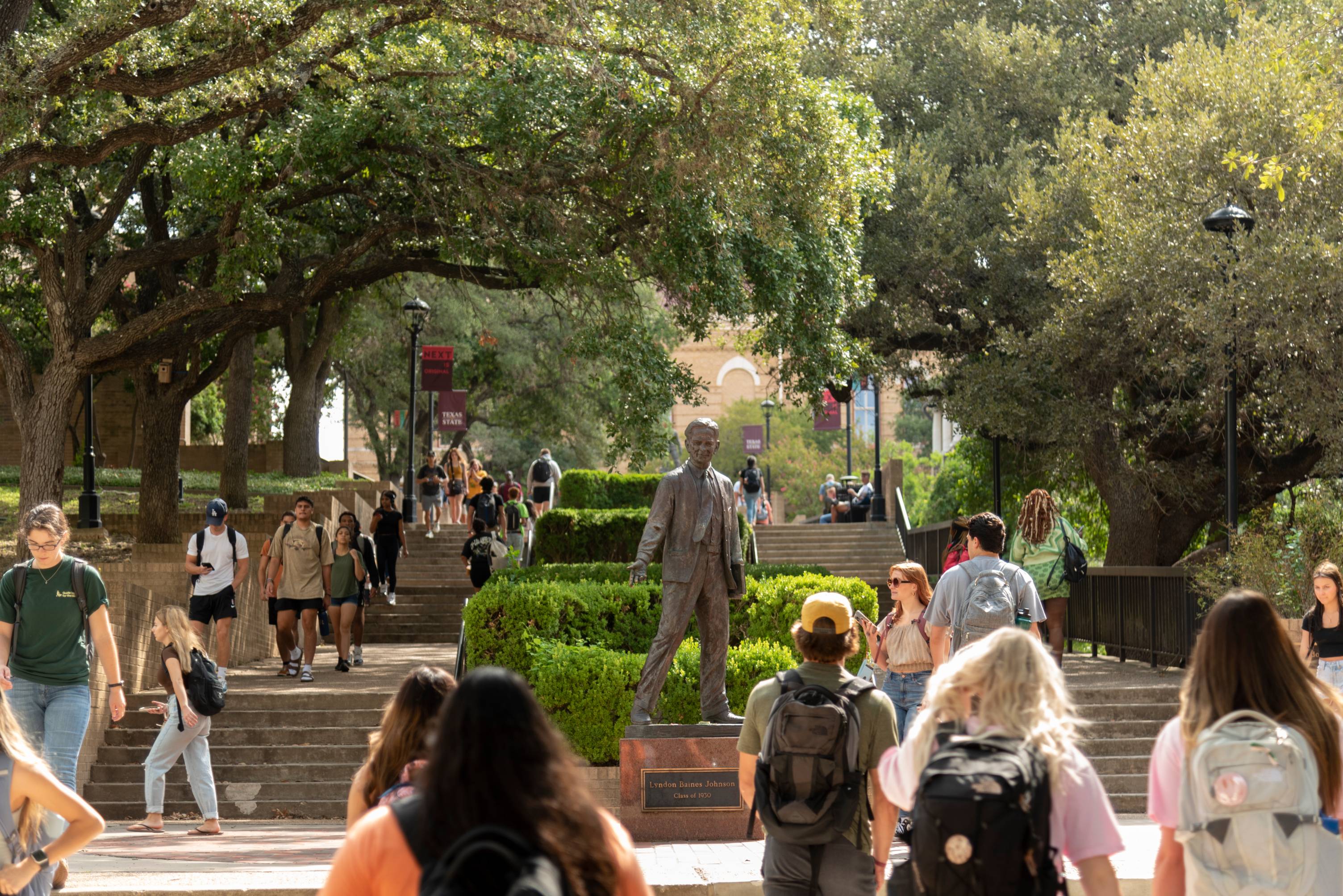 Students walking in the Quad past the statue of LBJ