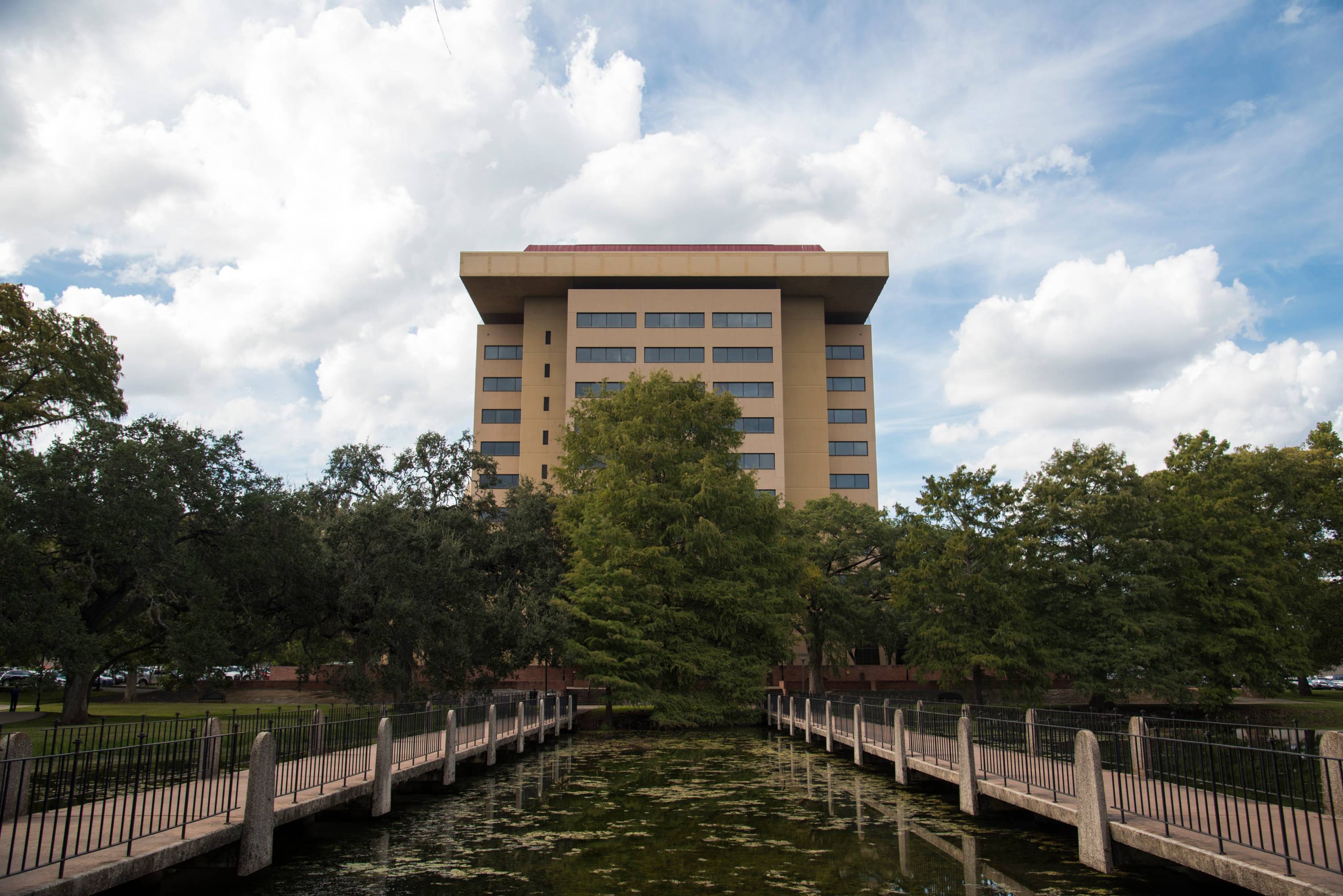 Two walking bridges over ponds leading to the J.C. Kellam Administration Building on a bright afternoon