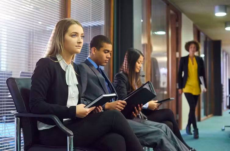 YOUNG PEOPLE IN BUSINESS ATTIRE WAITING FOR JOB INTERVIEW