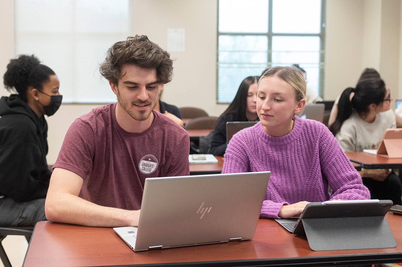 man and woman looking at computer in classroom