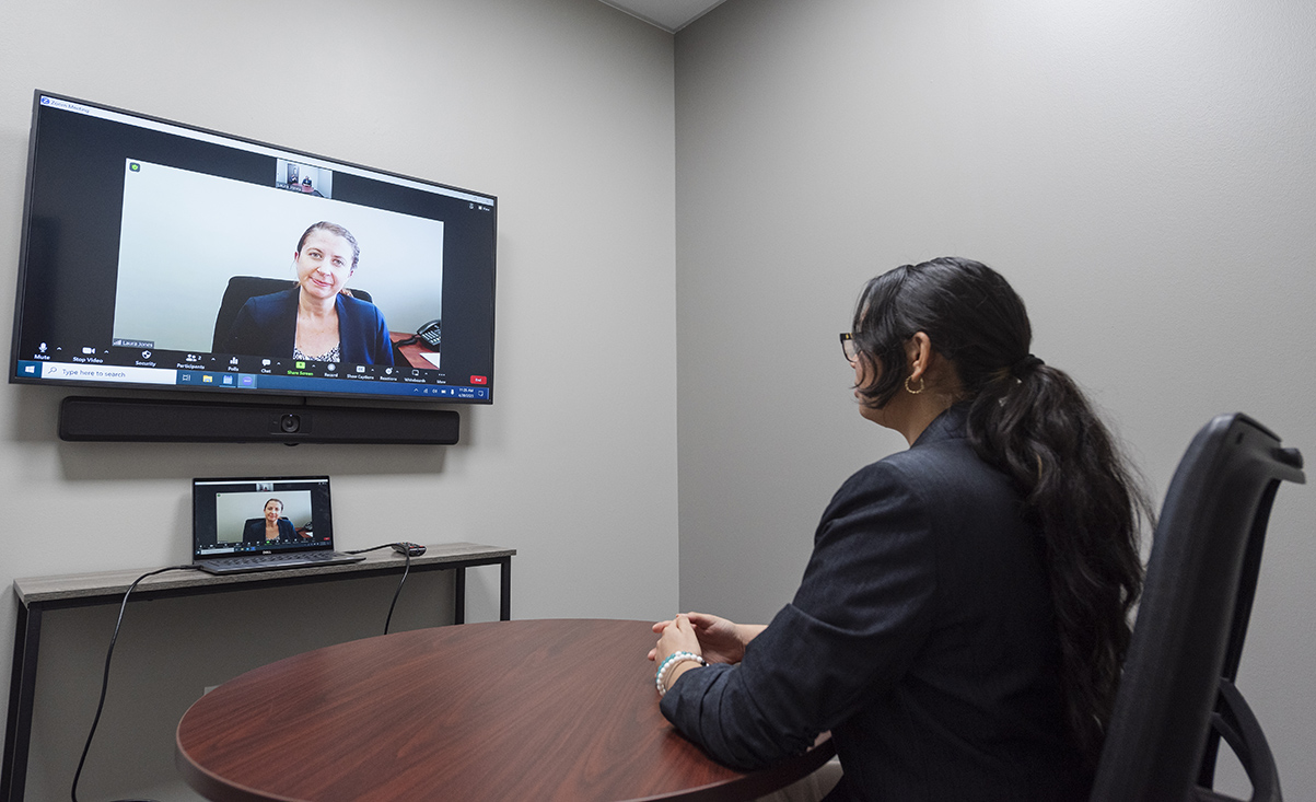 female student in virtual job interview with woman on wall-mounted tv