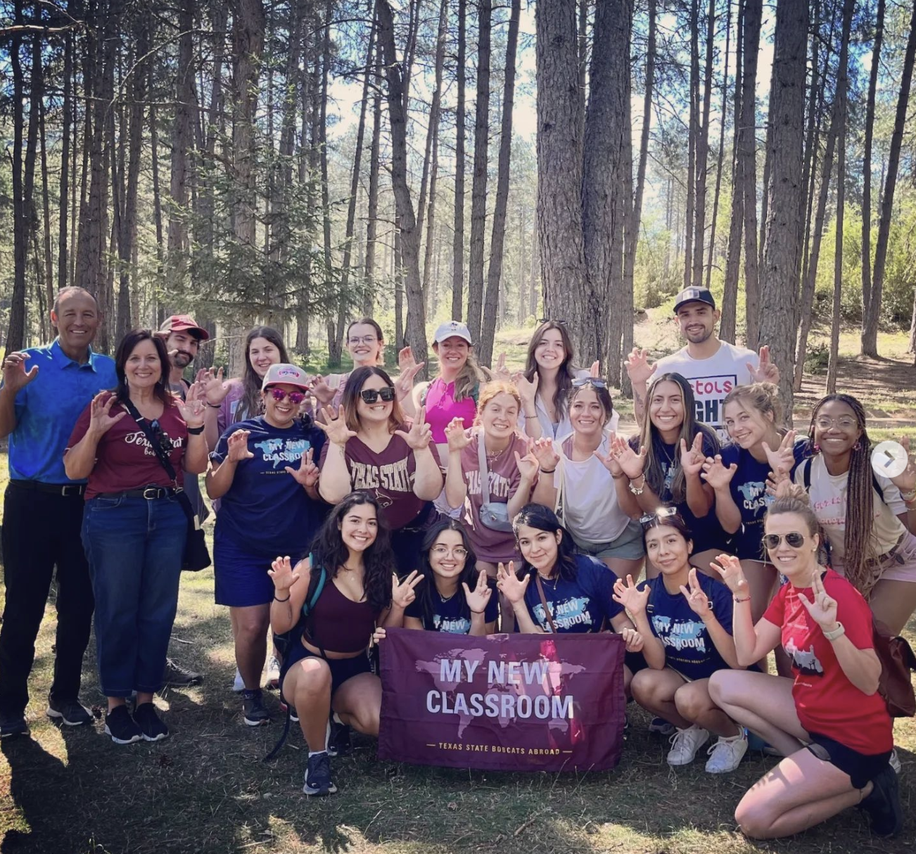 large group of people posing for photo with study abroad banner