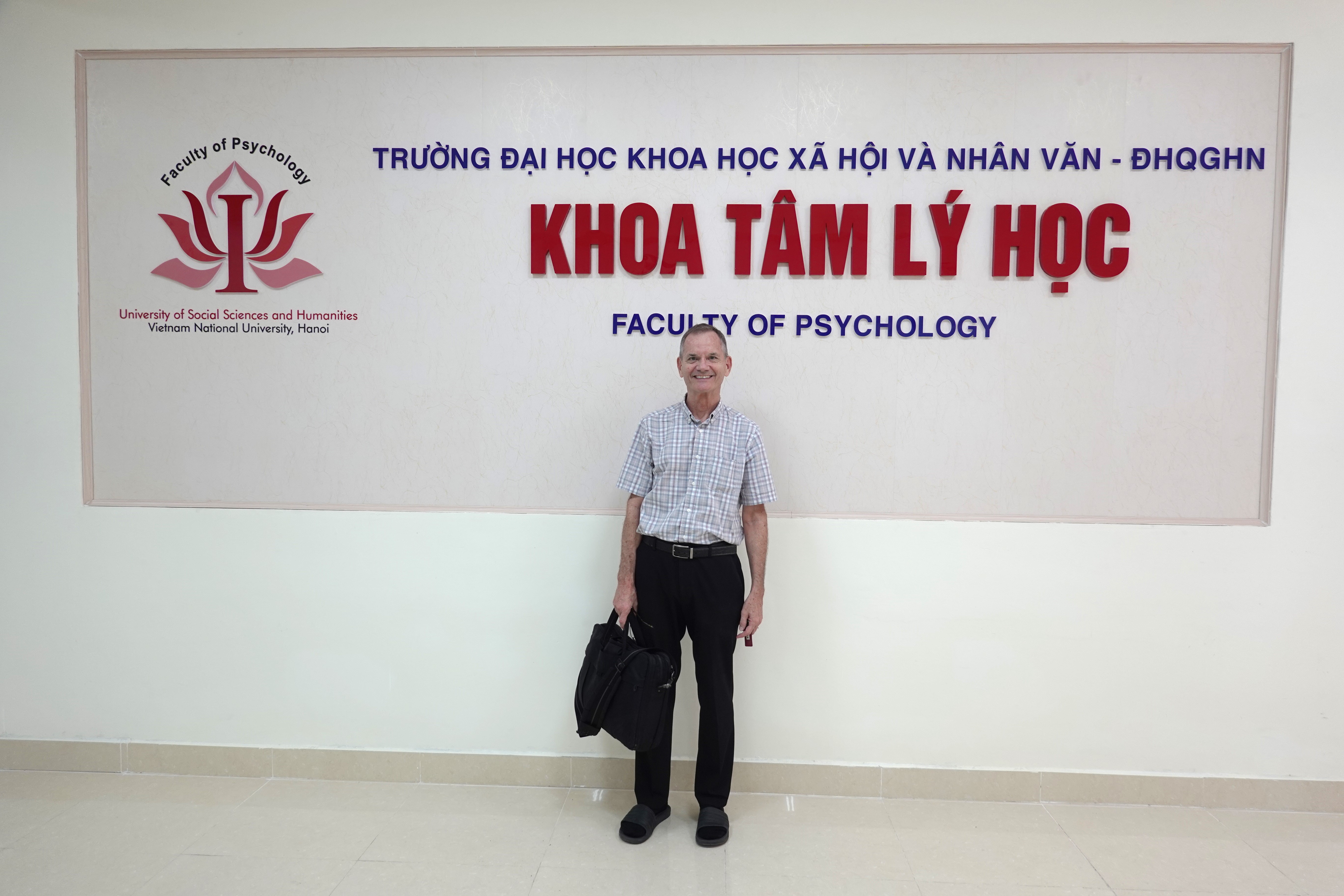 Picture of me standing in front of sign in English and Vietnamese that says " Faculty of Psycholoy, University of Social Sciences and Humanities, Vietnam National University""
