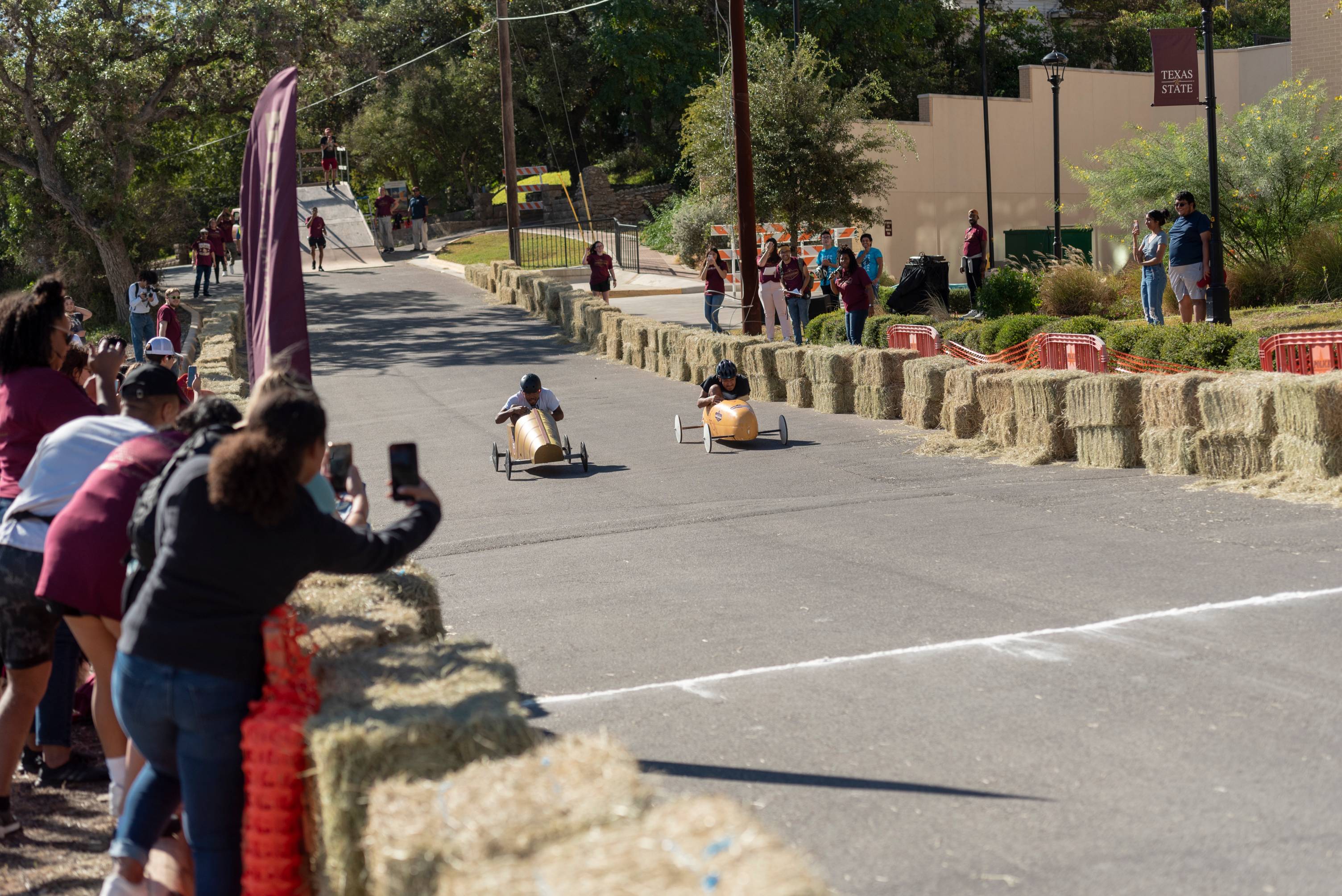 Two soap box cars racing towards a finish line 