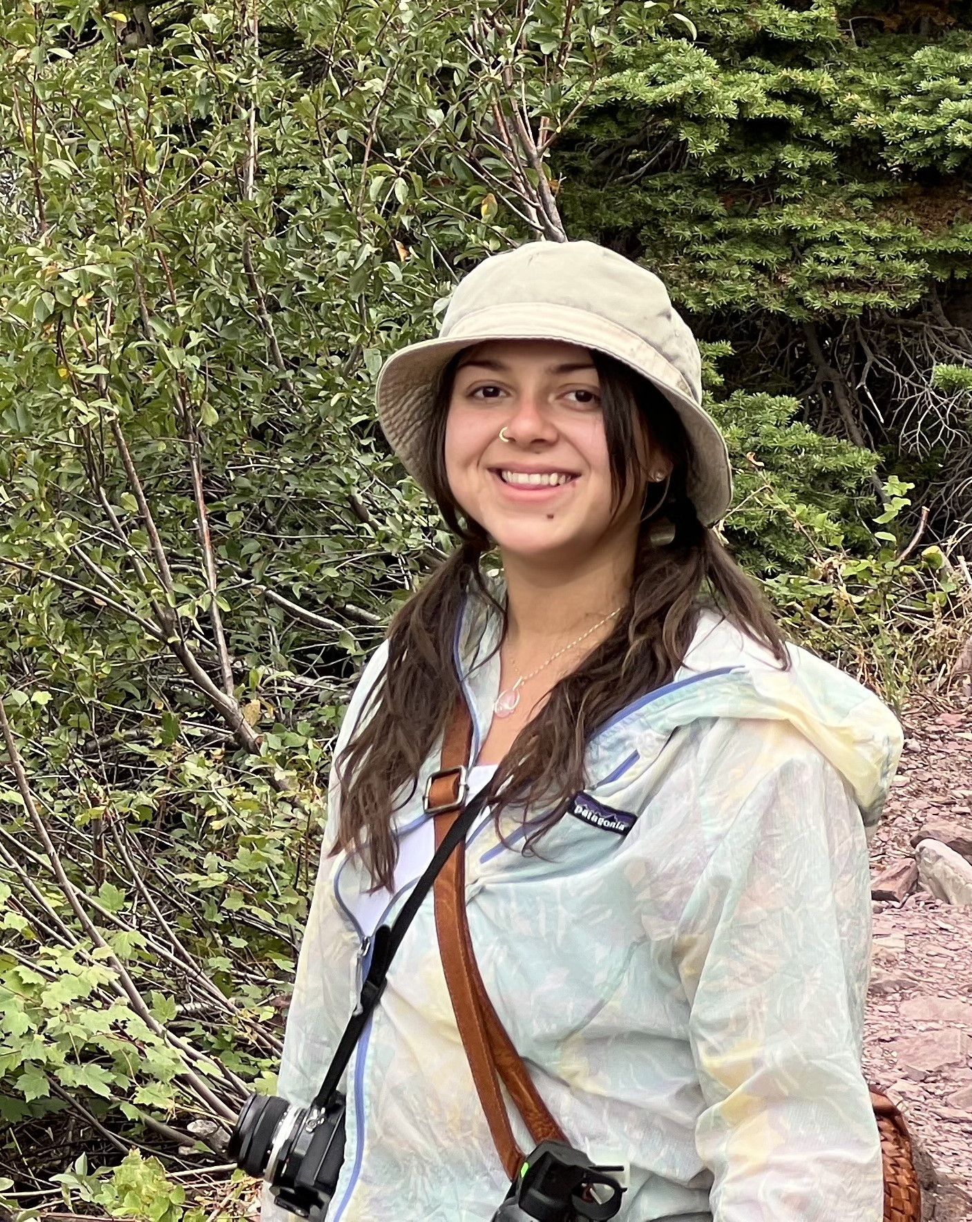 woman wearing rain hat and jacket standing in front of hiking trail