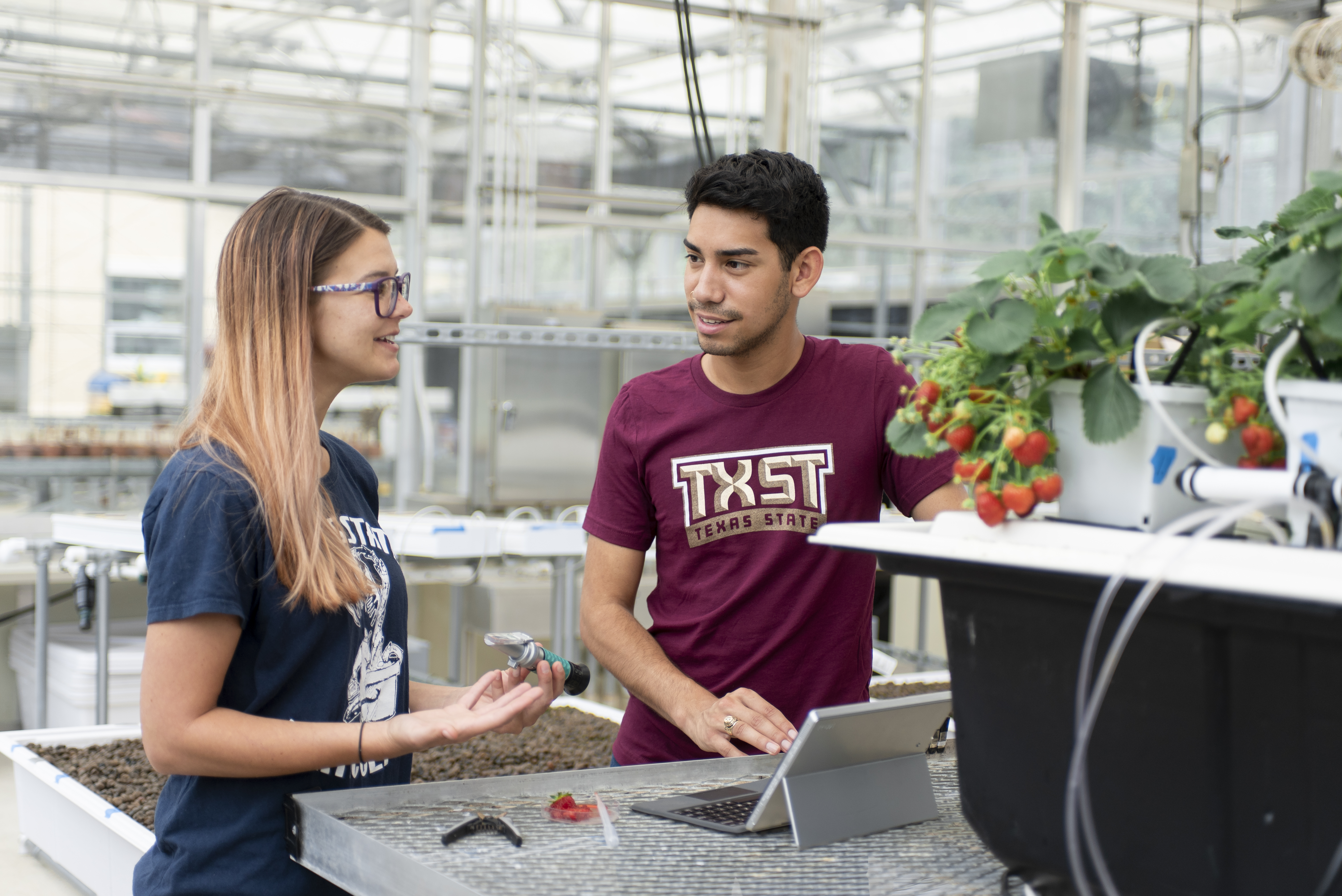 Two students from TXST discussing about agriculture in a greenhouse