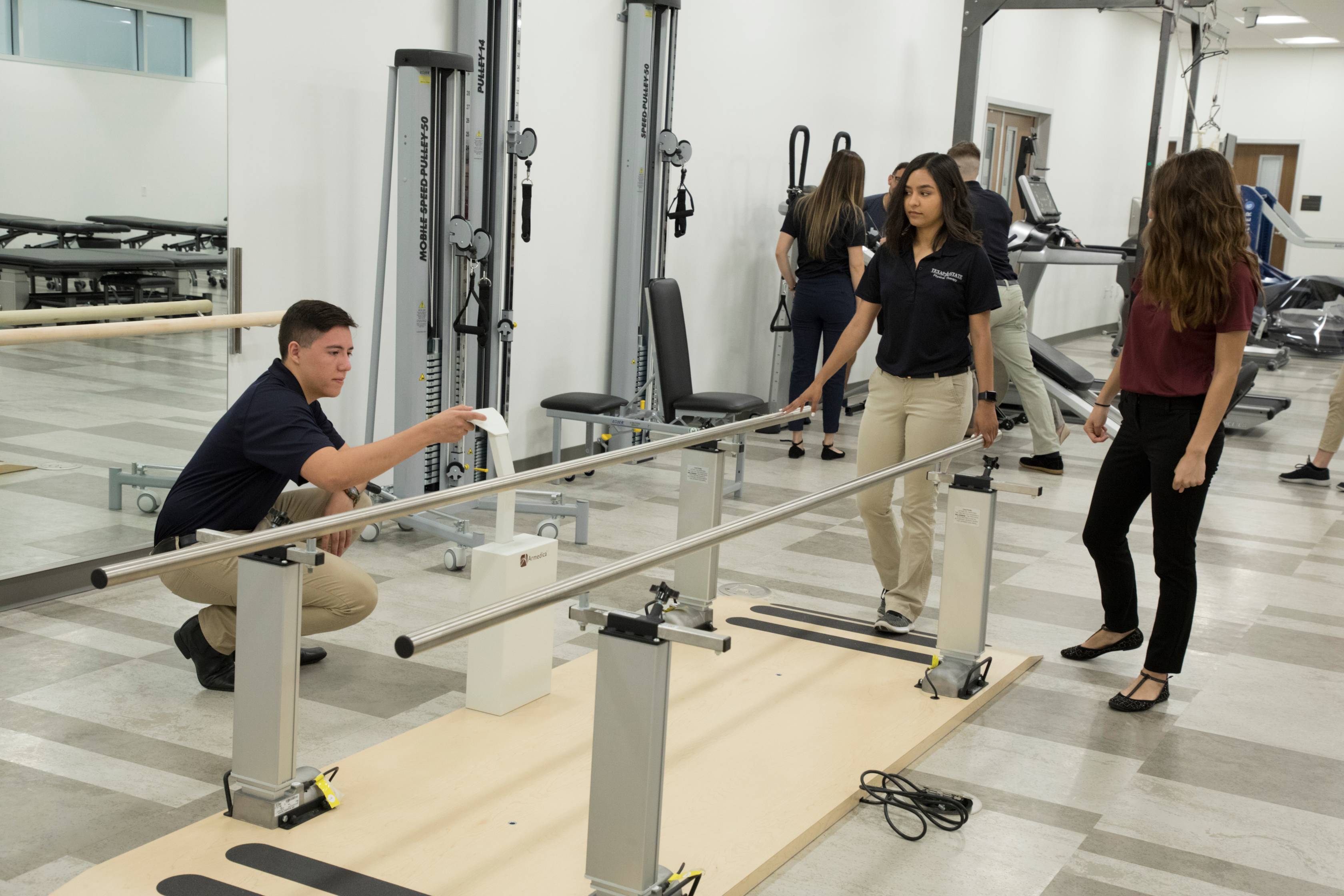 Individual stepping forward to use walking rails in Texas State's Physical Therapy Clinic at Round Rock,