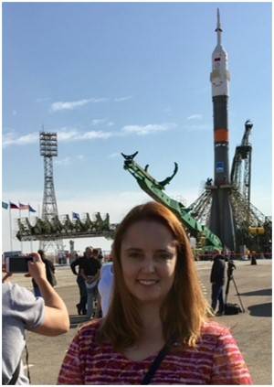 woman posing for photo in front of large rocket