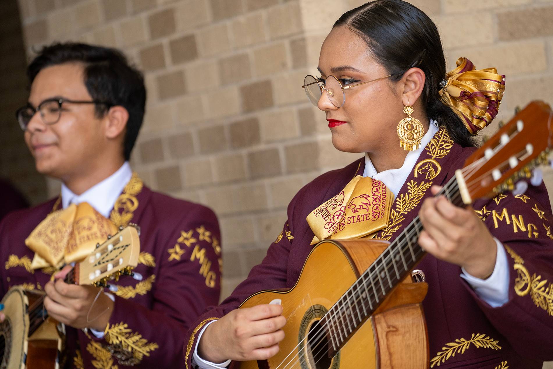 man and woman in mariachi band playing string instruments
