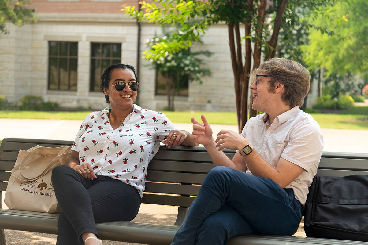 woman and man sitting on bench while having conversation