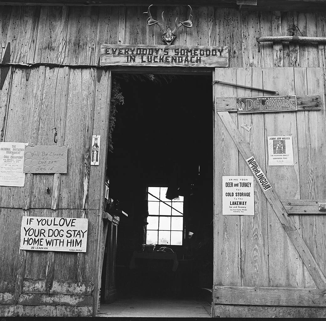 black and white photo of wooden building and signs on doors