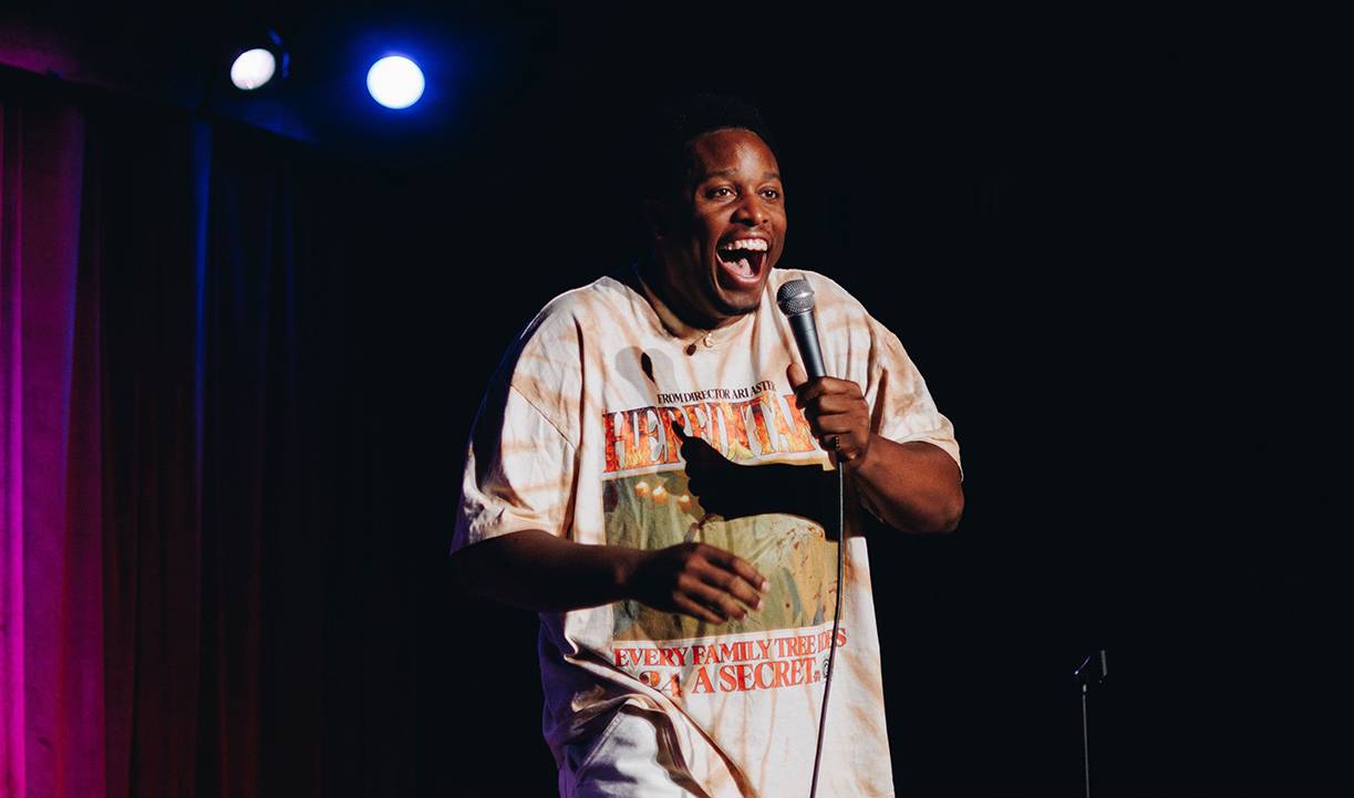 male comedian laughs while performing on stage