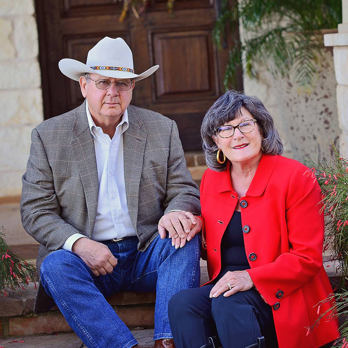man in cowboy hat and woman in red jacket smile