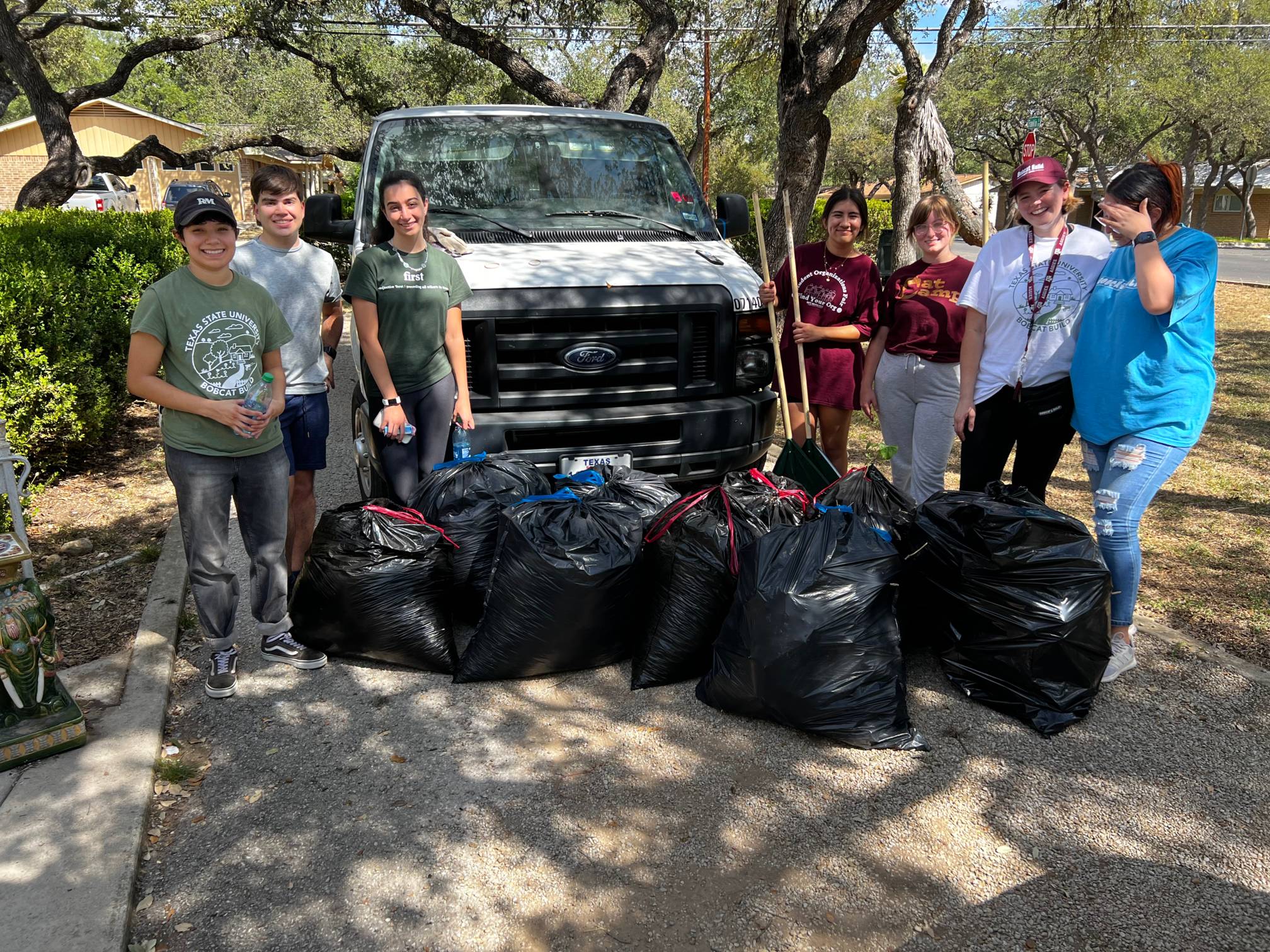 Students with trash bags full of brush