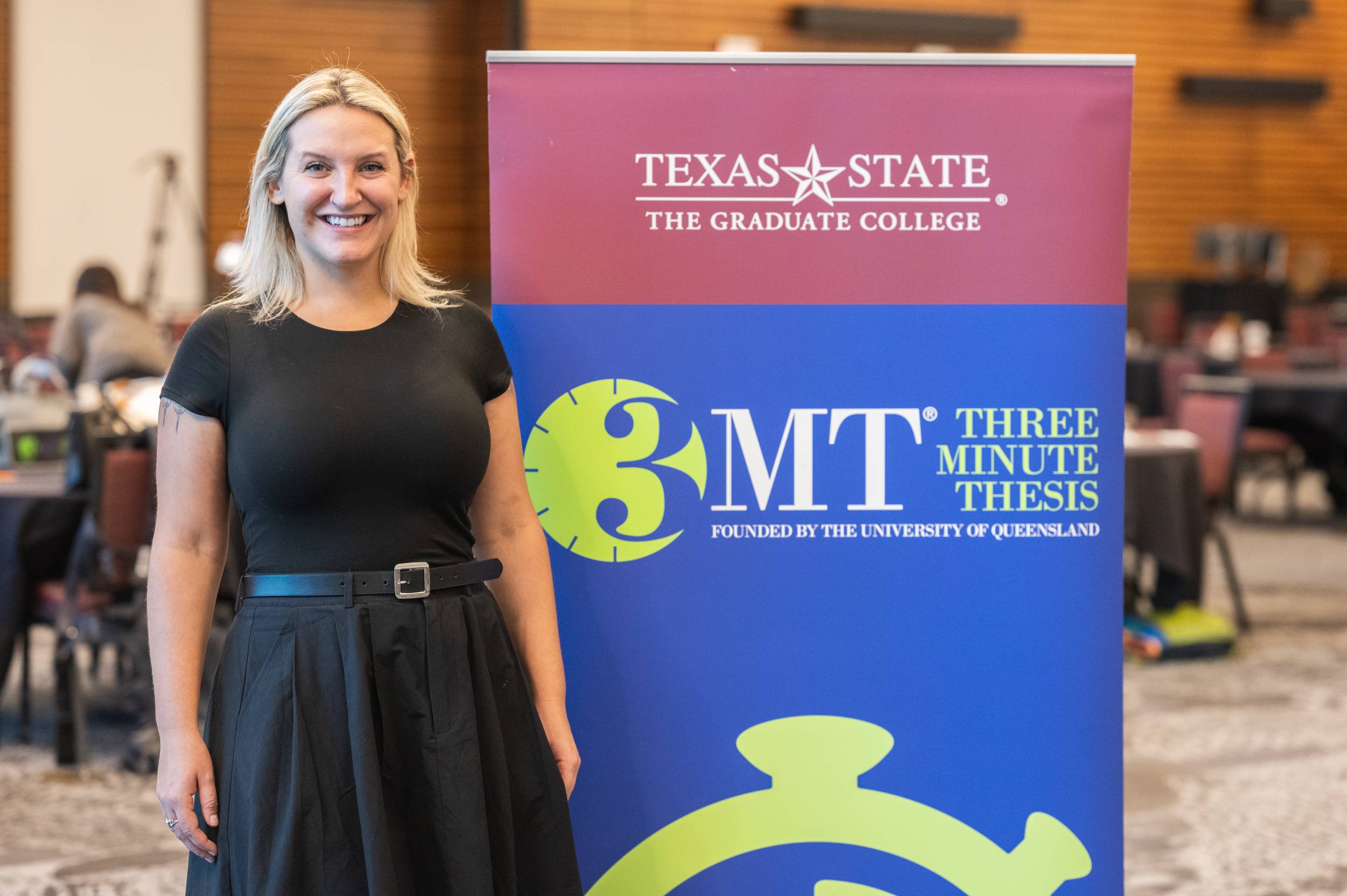 Brianna Fogel standing next to a 3MT sign holding her name tag and runner-up annoucement