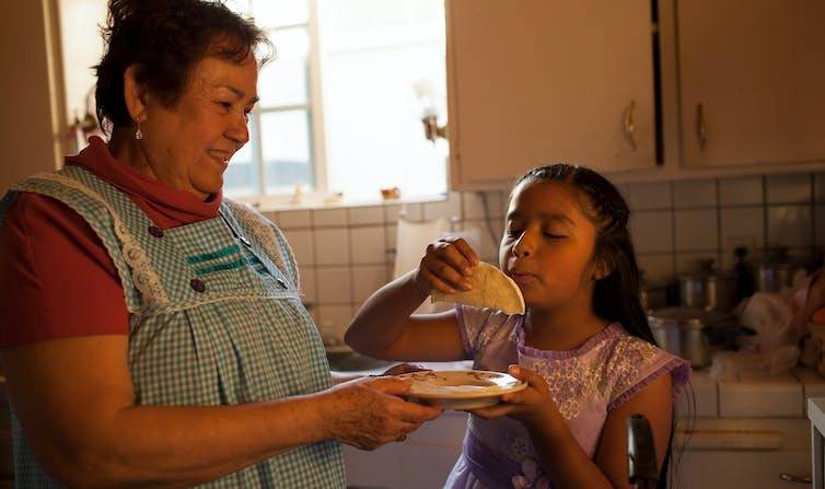 latina woman and child looking at food in kitchen