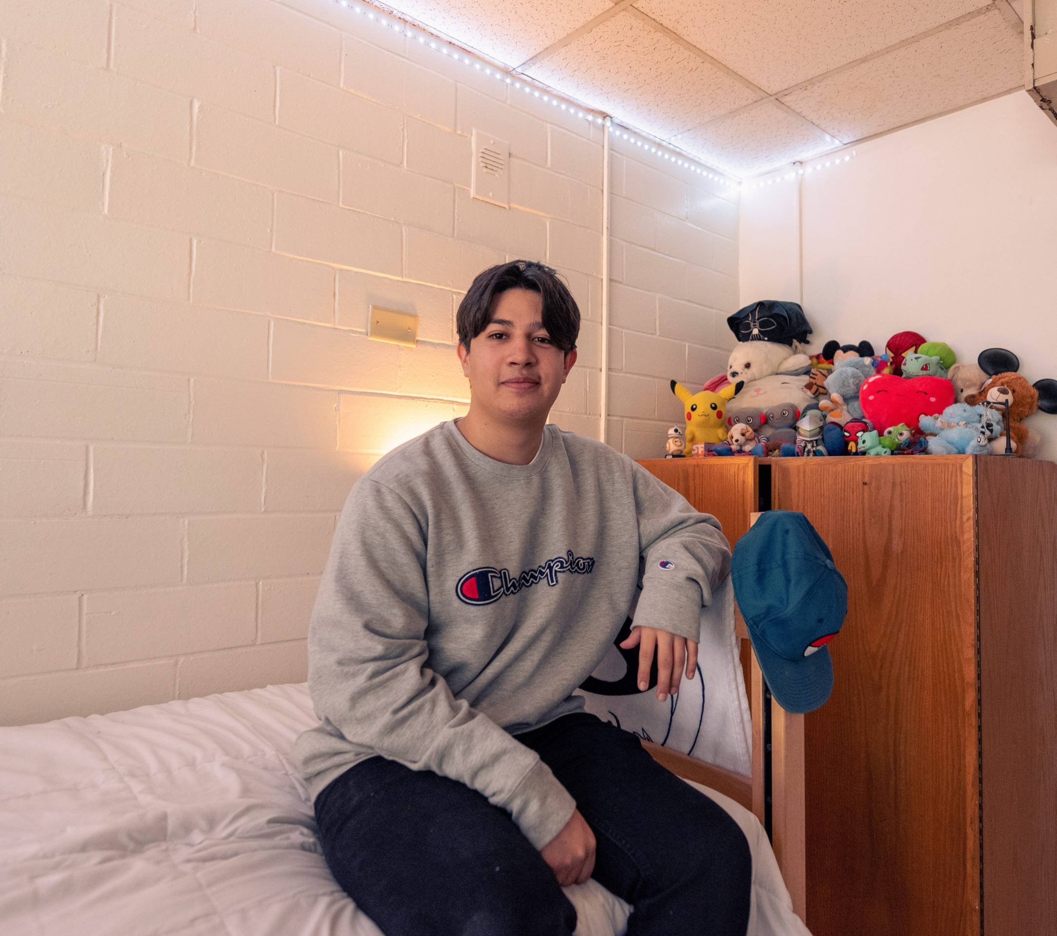 student sitting on their dorm room bed