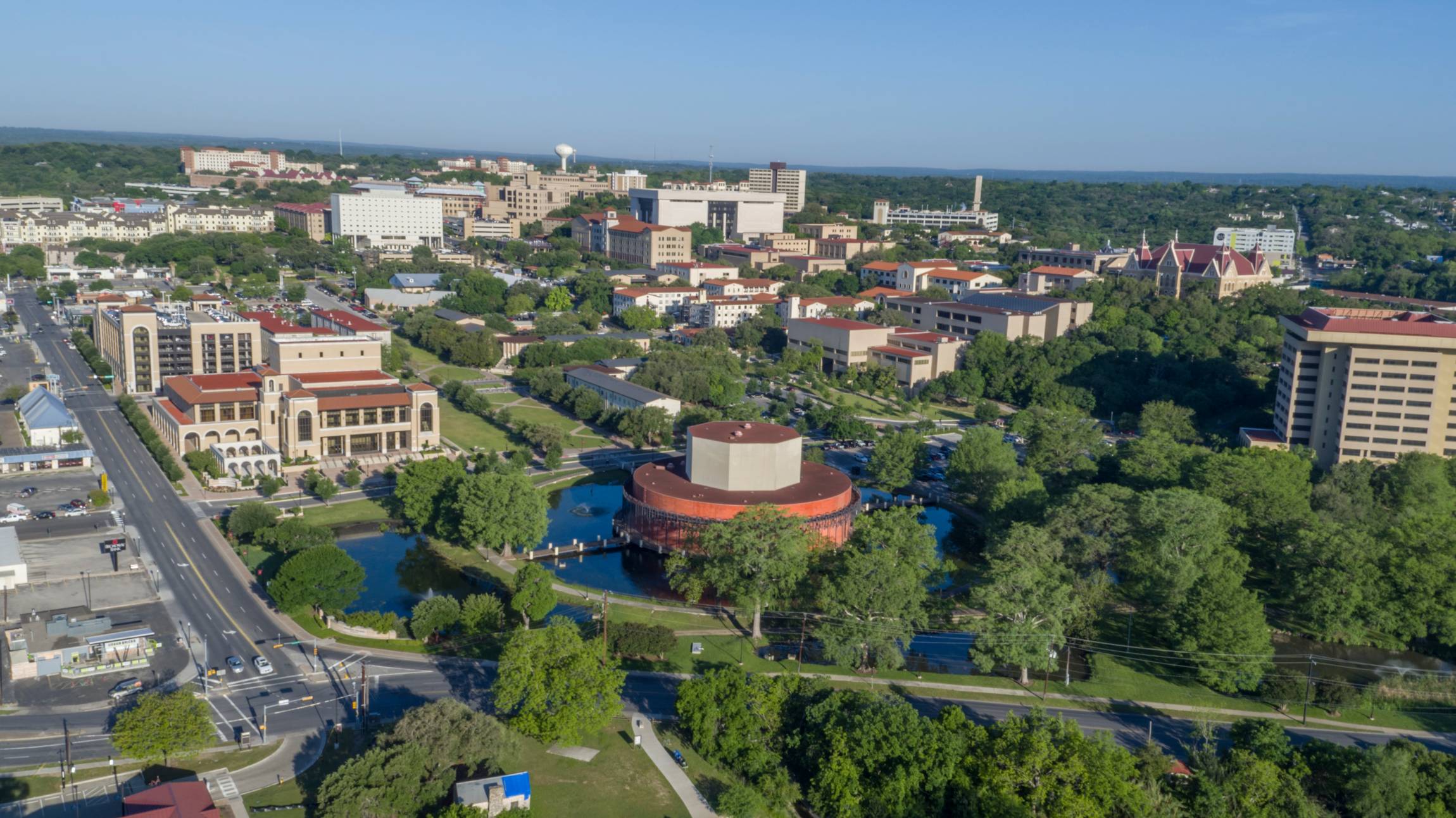 A drone shot of TXST campus looking onto the theater building and University Drive on a bright sunny day.