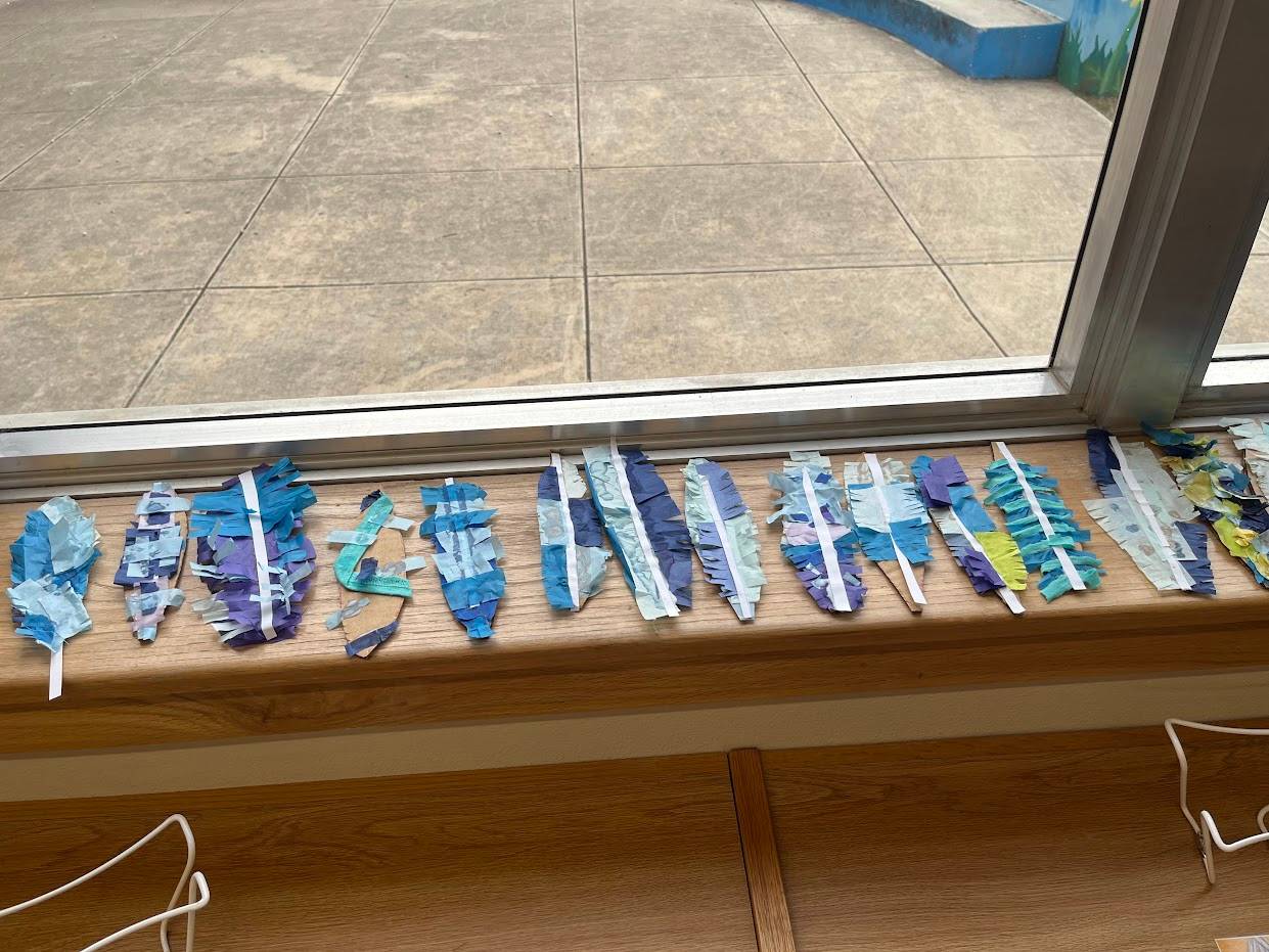 Feathers made of recycled materials lay out to dry on a windowsill.