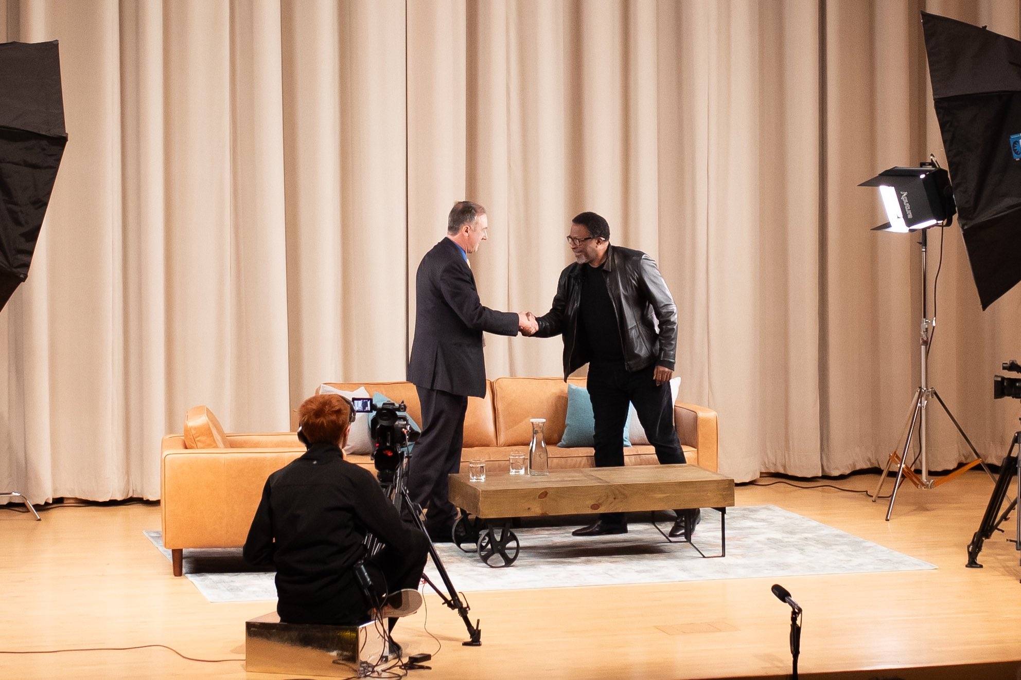Dean John Fleming, left, shakes Thomas Carter's hand on stage during the alumni Q&A.