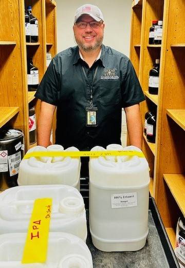 Hazardous Waste Technician, Joseph Krupa, posing for a picture behind 3 full carboys. 