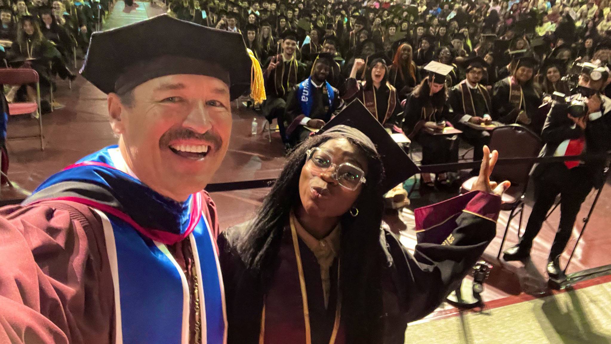 President Damphousse, left, poses for a photo with the last graduate at commencement.