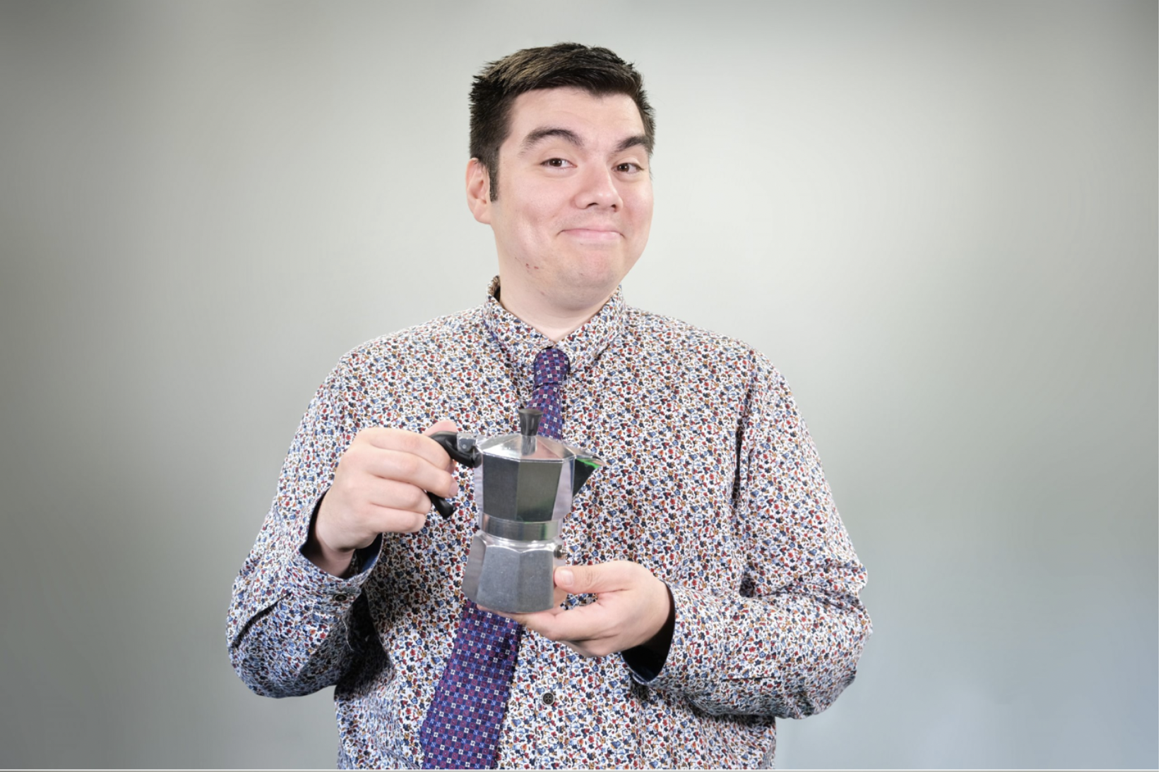 Man wearing colorful shirt and tie, holding a moka pot